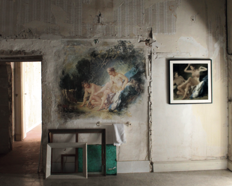 Intérieur d'une pièce avec deux tableaux représentant des figures humaines, murs en pierre en mauvais état, porte entrouverte, objets de décoration au sol.