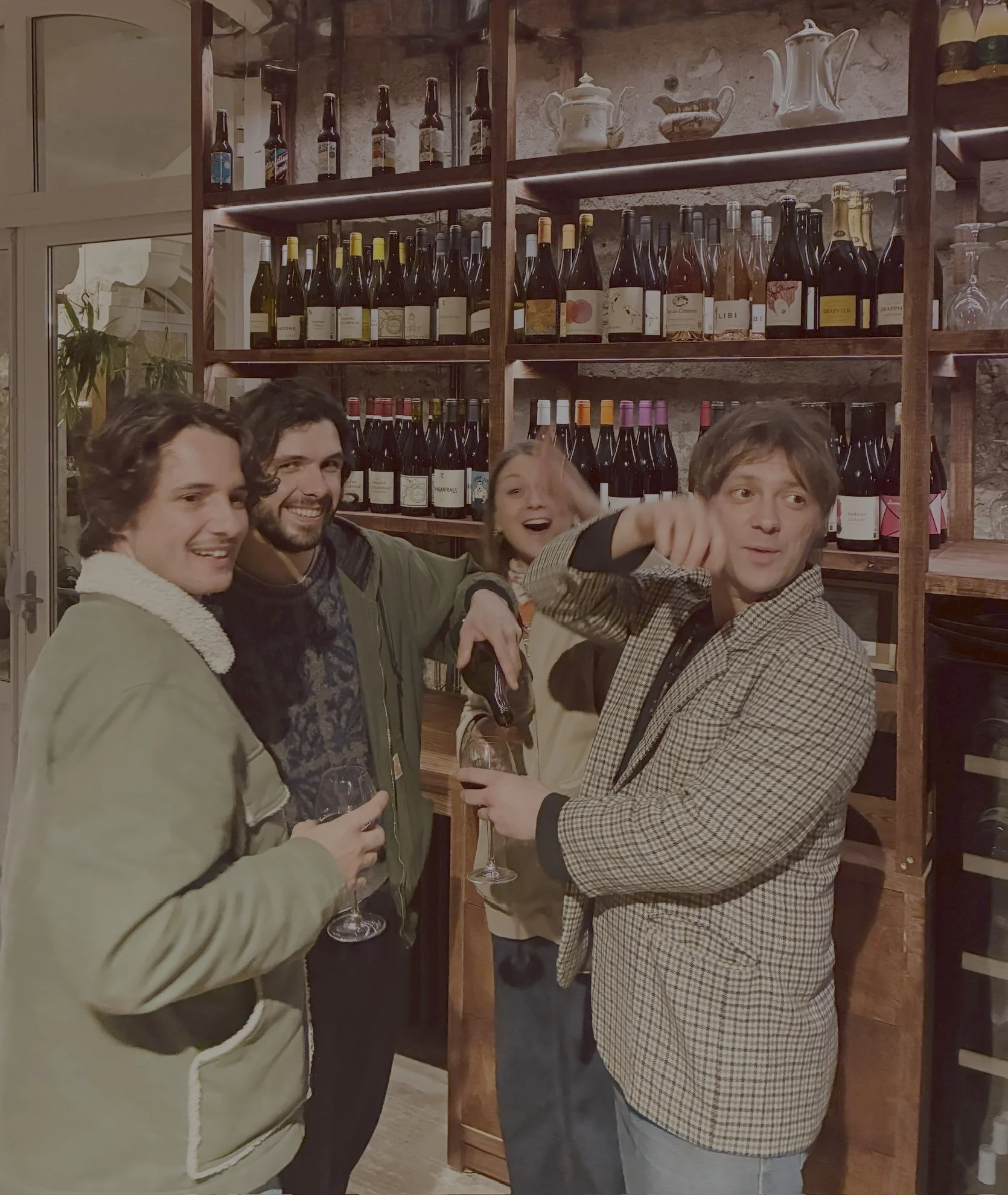 Groupe de quatre personnes souriantes dégustant du vin dans une cave à vin.