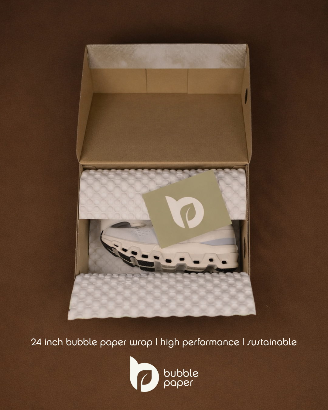 Open cardboard box with white bubble paper wrap, sneakers, and a green card with a white leaf logo that reads 'bubble paper'.