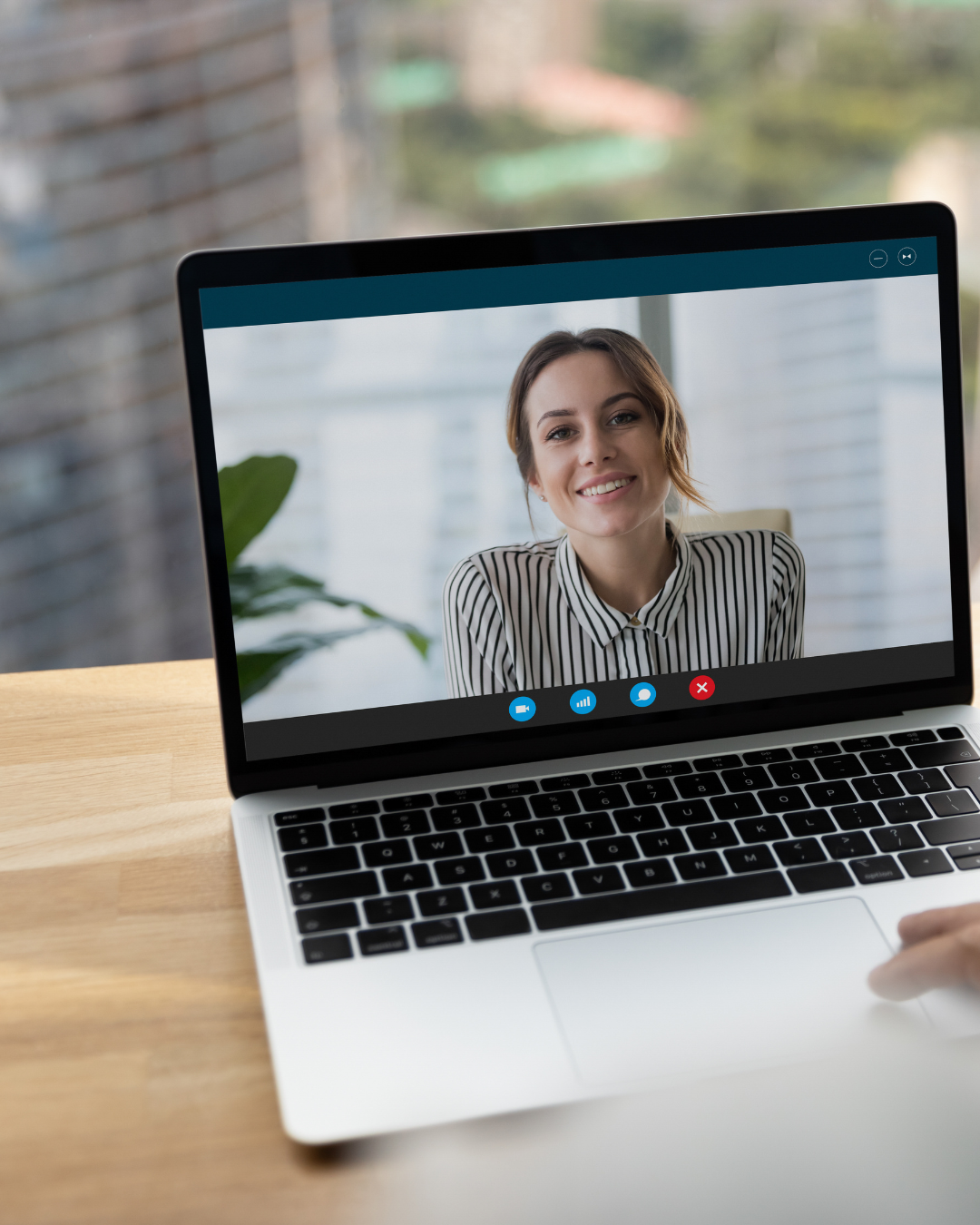 Laptop screen showing a smiling woman in a striped shirt during a video call.