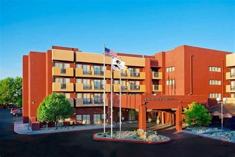 Exterior view of a multi-story hotel building with flagpoles and landscaped entrance.