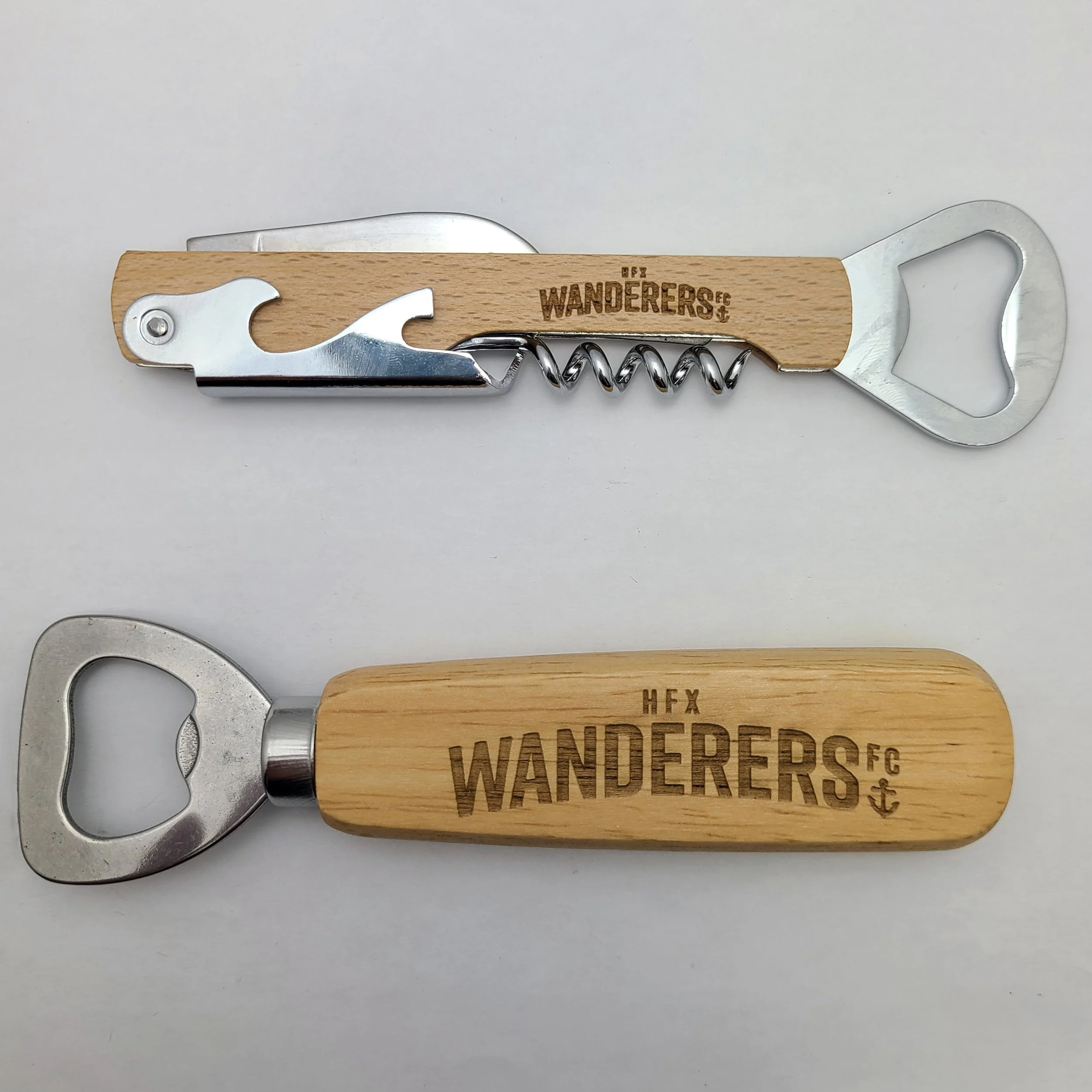 A corkscrew and bottle opener with wooden handles engraved with the words 'WANDERERS FC' and an anchor symbol.