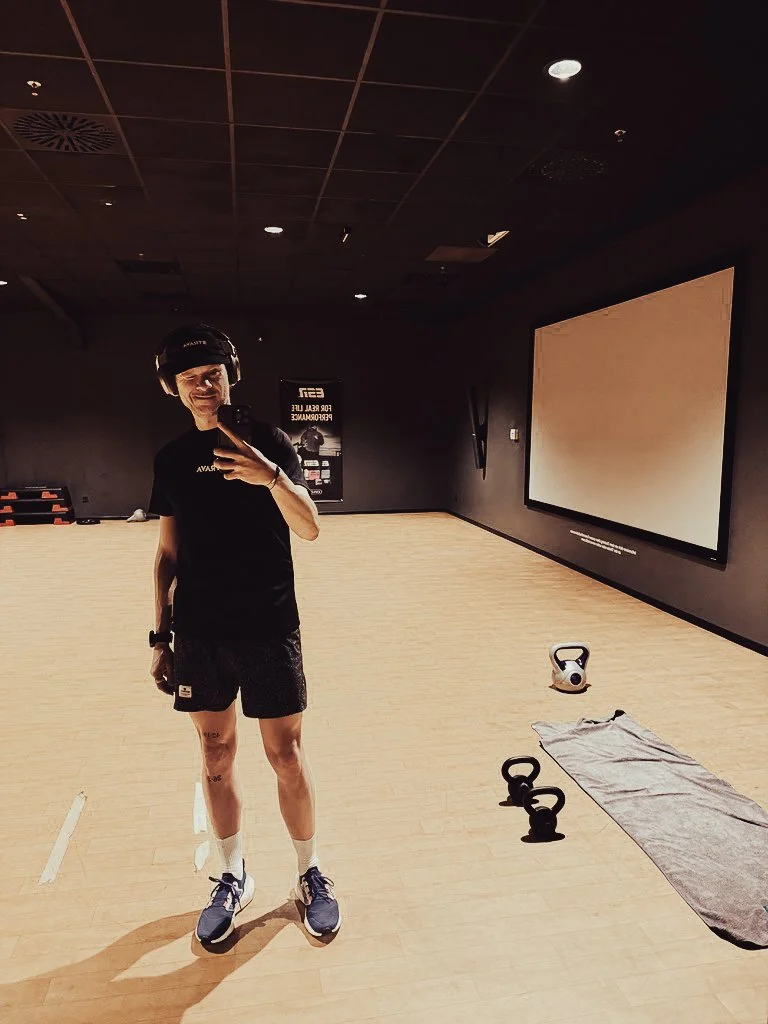 Läufer macht Selfie im Fitnessstudio neben Kettle-Balls und Yoga-Matte