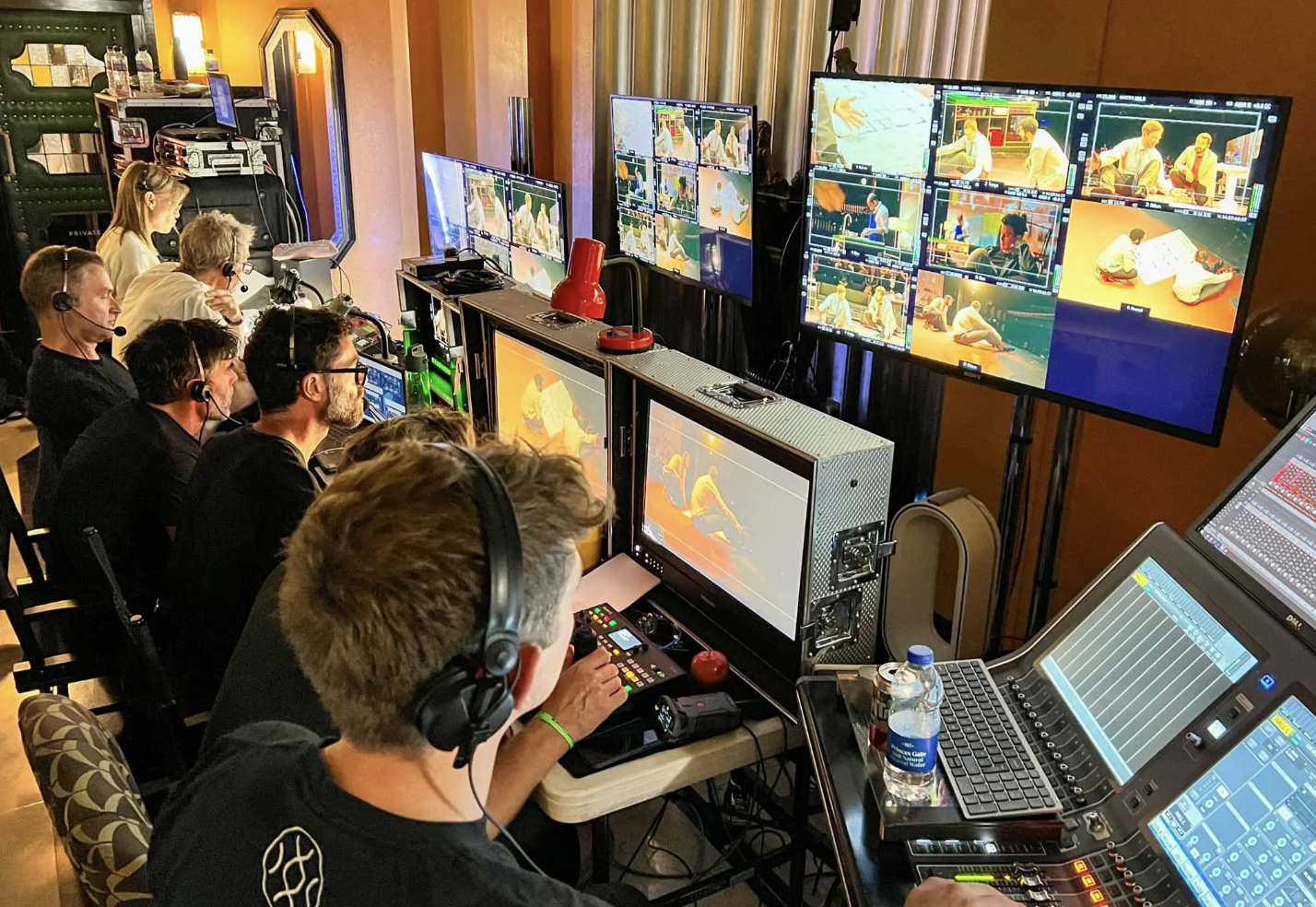 Video production team operating multiple monitors and equipment displaying footage of people practicing martial arts.