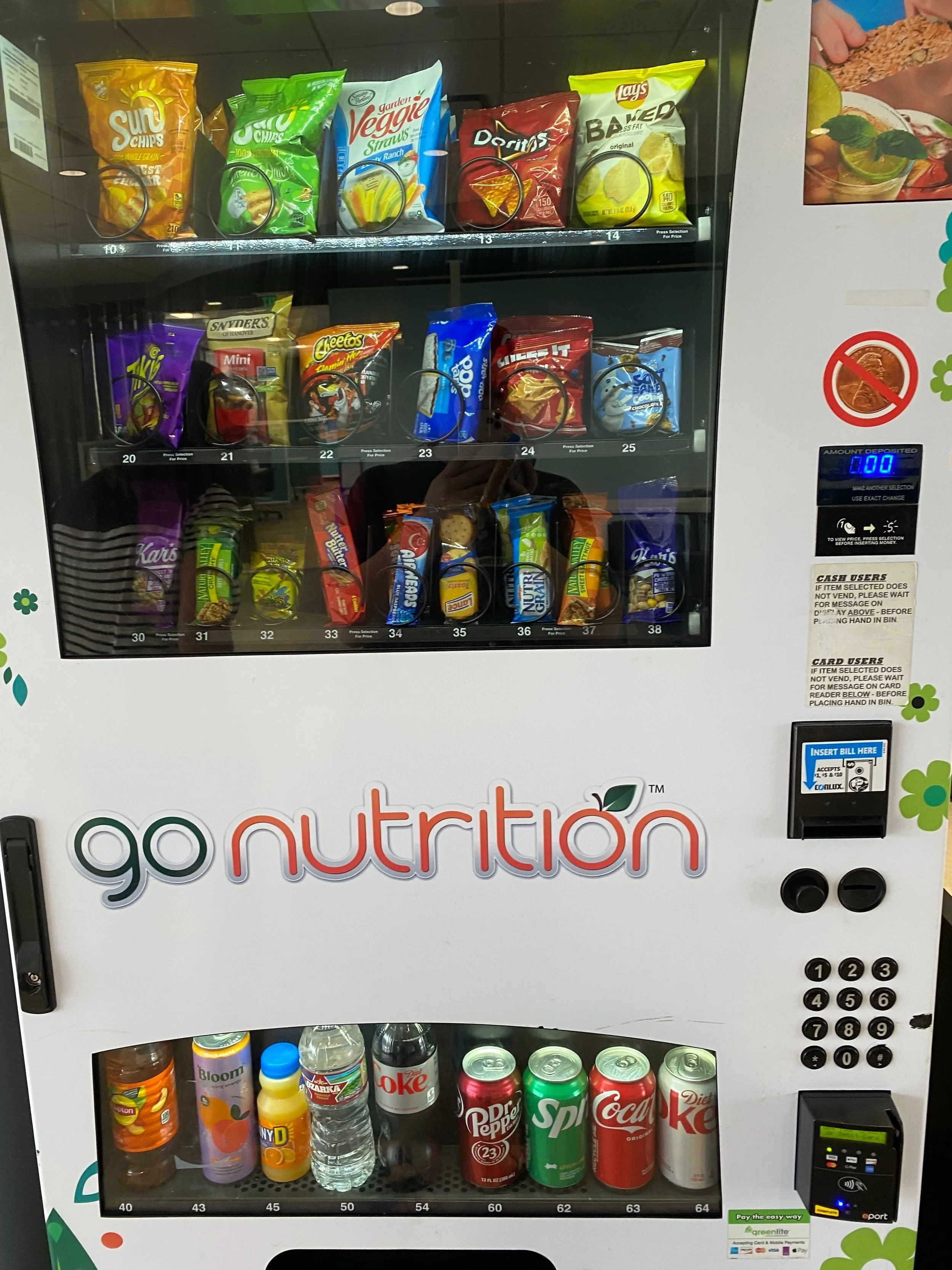 Vending machine with snacks on the top row including Sun Chips, garden veggie STRAWS, Doritos, Lay's Baked, Snyder's Minis, Cheetos, and Oreo cookies. The middle row has candies like Kar's trail mix and Reese's, Snickers, Reese's, and other chocolate bars. The bottom row holds beverages including Dr. Pepper, Sprite, Coca-Cola, and Diet Coke, along with a water bottle, a juice, and a bottled water.