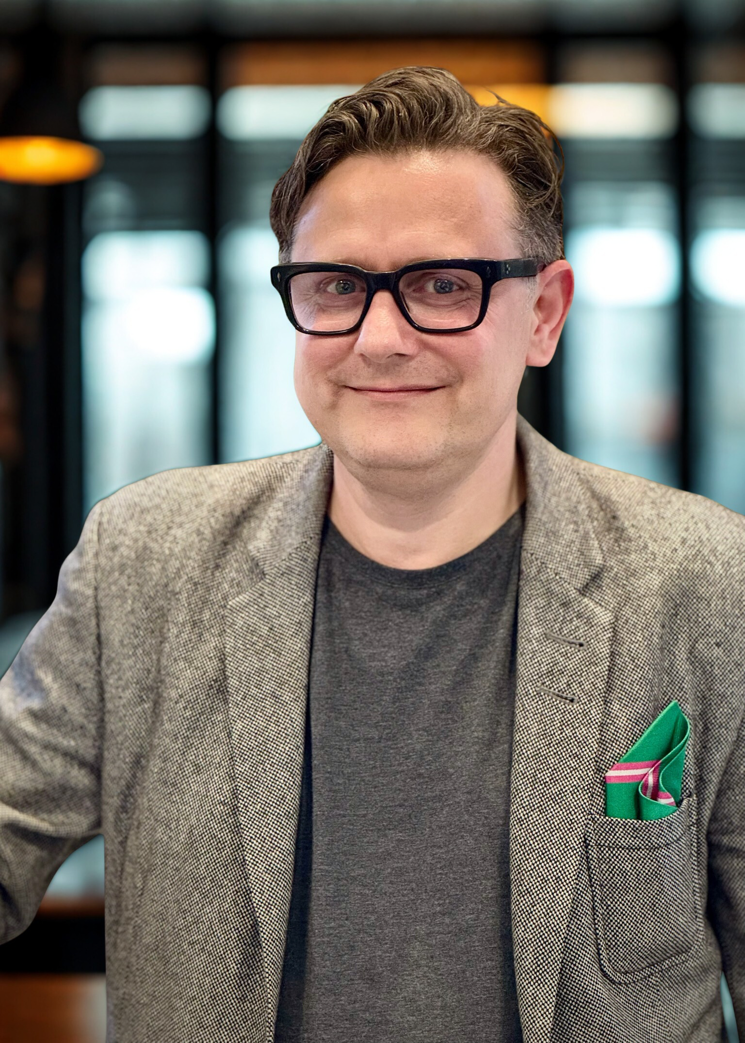 Mand i grålig blazer med mørkgrå trøje under og har sorte briller på, mørkt hår, New Yorker glasrude baggrund,  Michael Pelle Meiborg ASA LASER Nordic Business Manager DK & FI