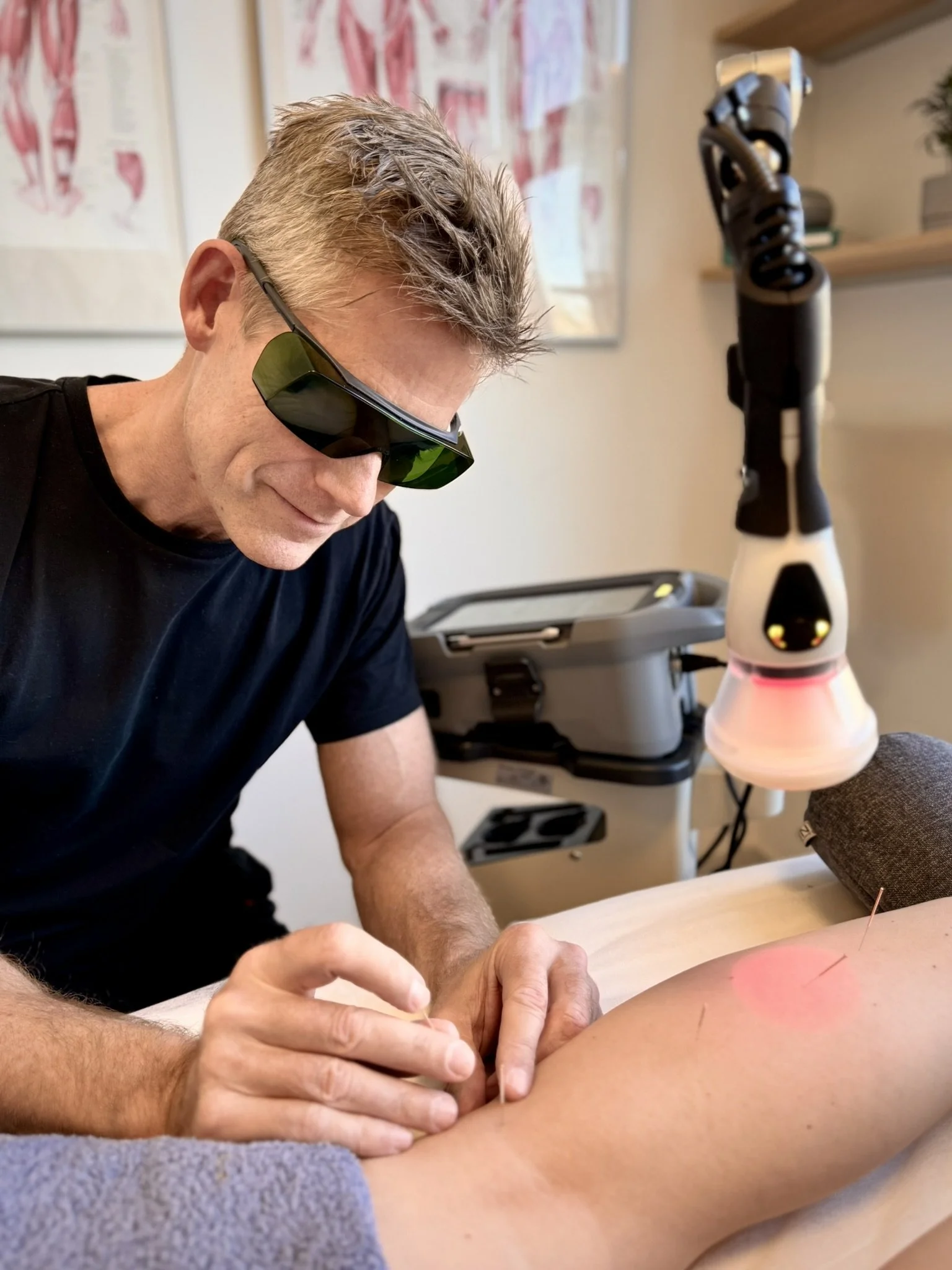 Behandler bruger ASAlaser beskyttelsesbriller under laserbehandling af arm. Sikkerhedsbriller til mennesker ved medicinsk laserterapi.