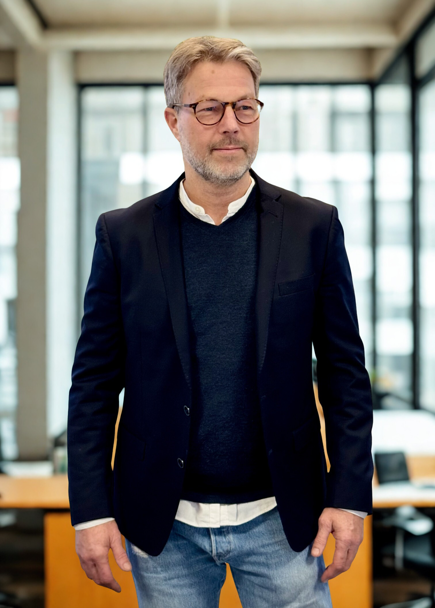 En mand med sorte blazer jakke og hvid skjorte og gråsprængt hår, New Yorker glasrude baggrund -  Claus Andersen