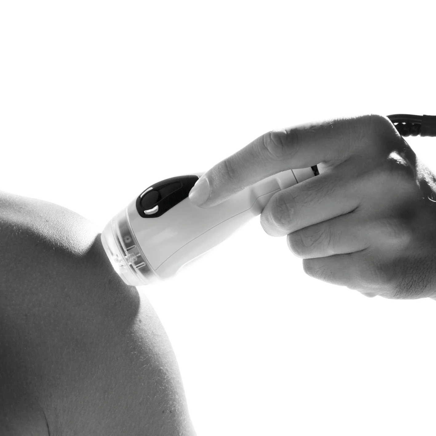 A person is receiving a close-up ultrasound scan on their shoulder using a handheld laser device.