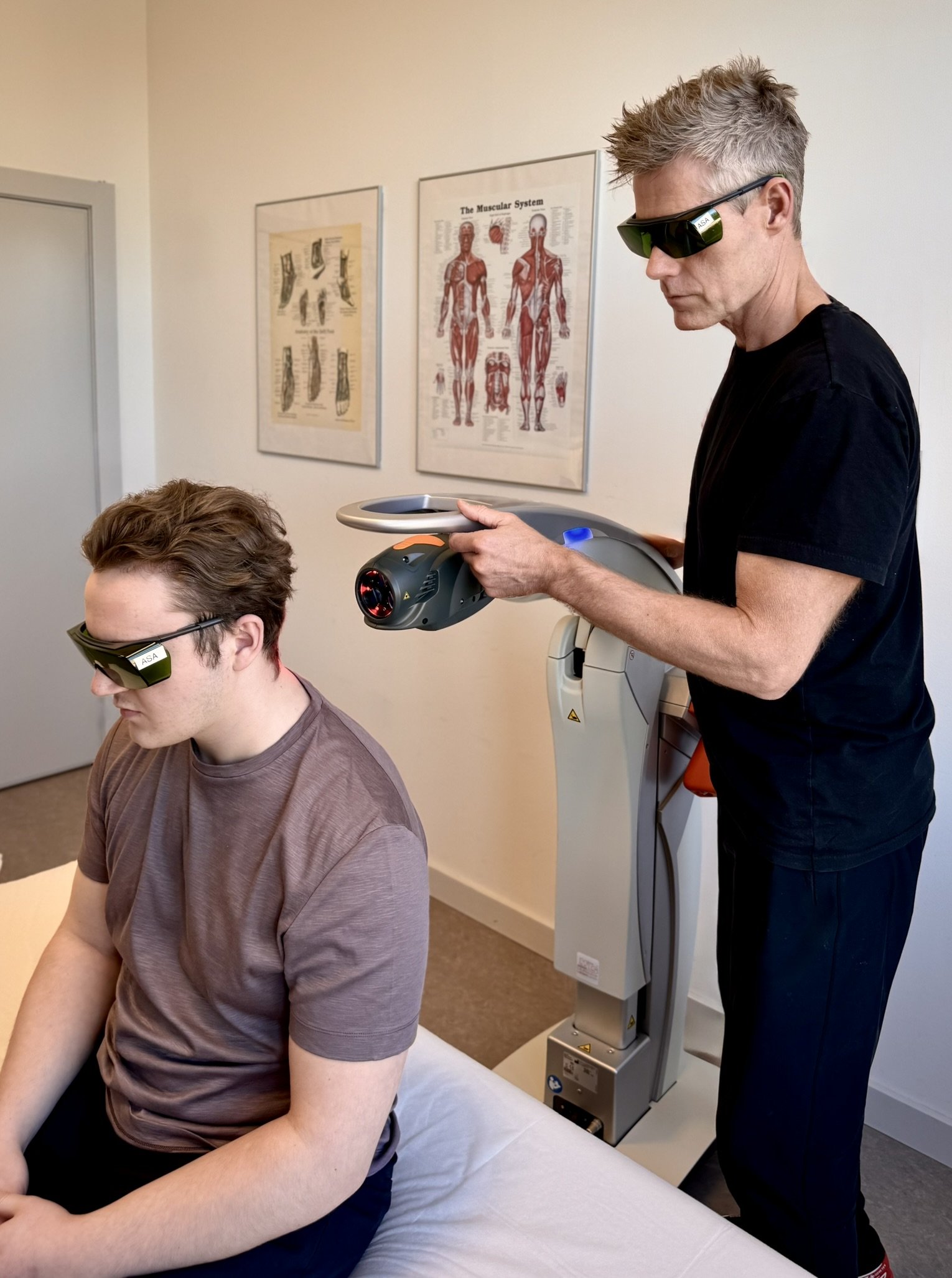 Patient og behandler med ASAlaser sikkerhedsbriller ved laserbehandling af nakke og skulder. Laserbriller til sikker medicinsk behandling.
