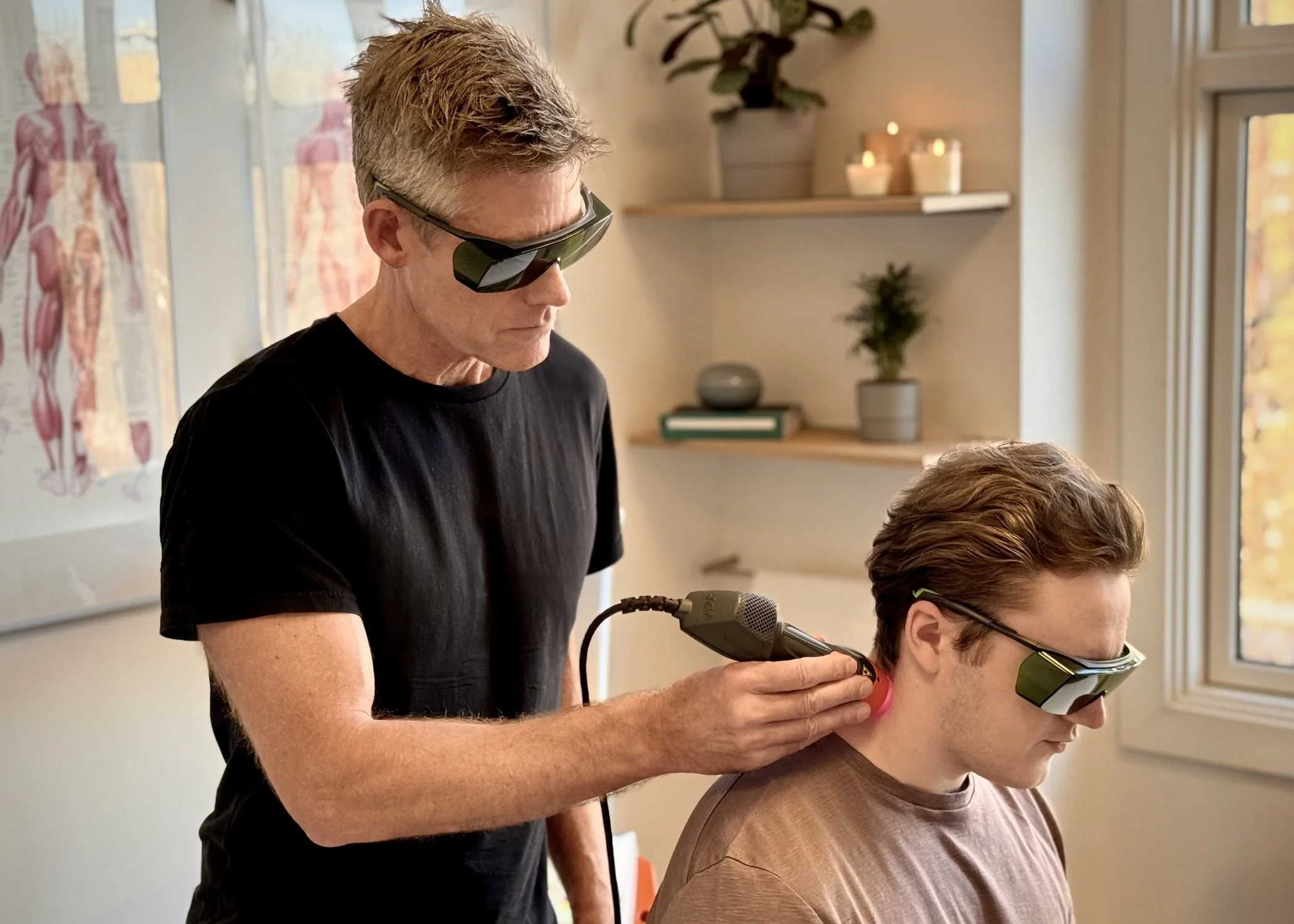 Patient og behandler med ASAlaser laserbriller under behandling af nakke. Beskyttelsesbriller til mennesker ved sikker laserterapi.