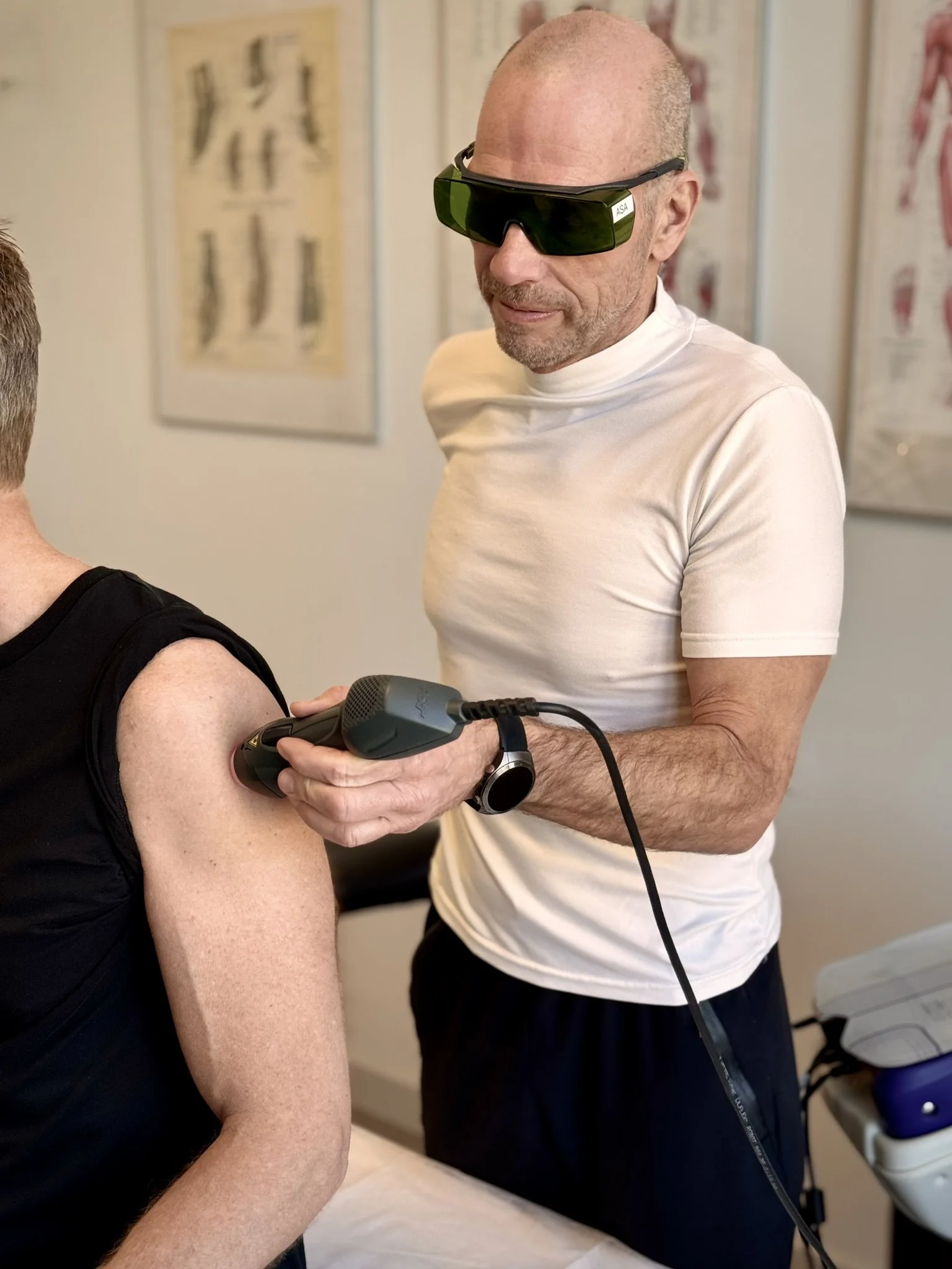 Behandler med ASAlaser beskyttelsesbriller under målrettet laserterapi af knæ. Øjenbeskyttelse til brug ved medicinsk laserudstyr.