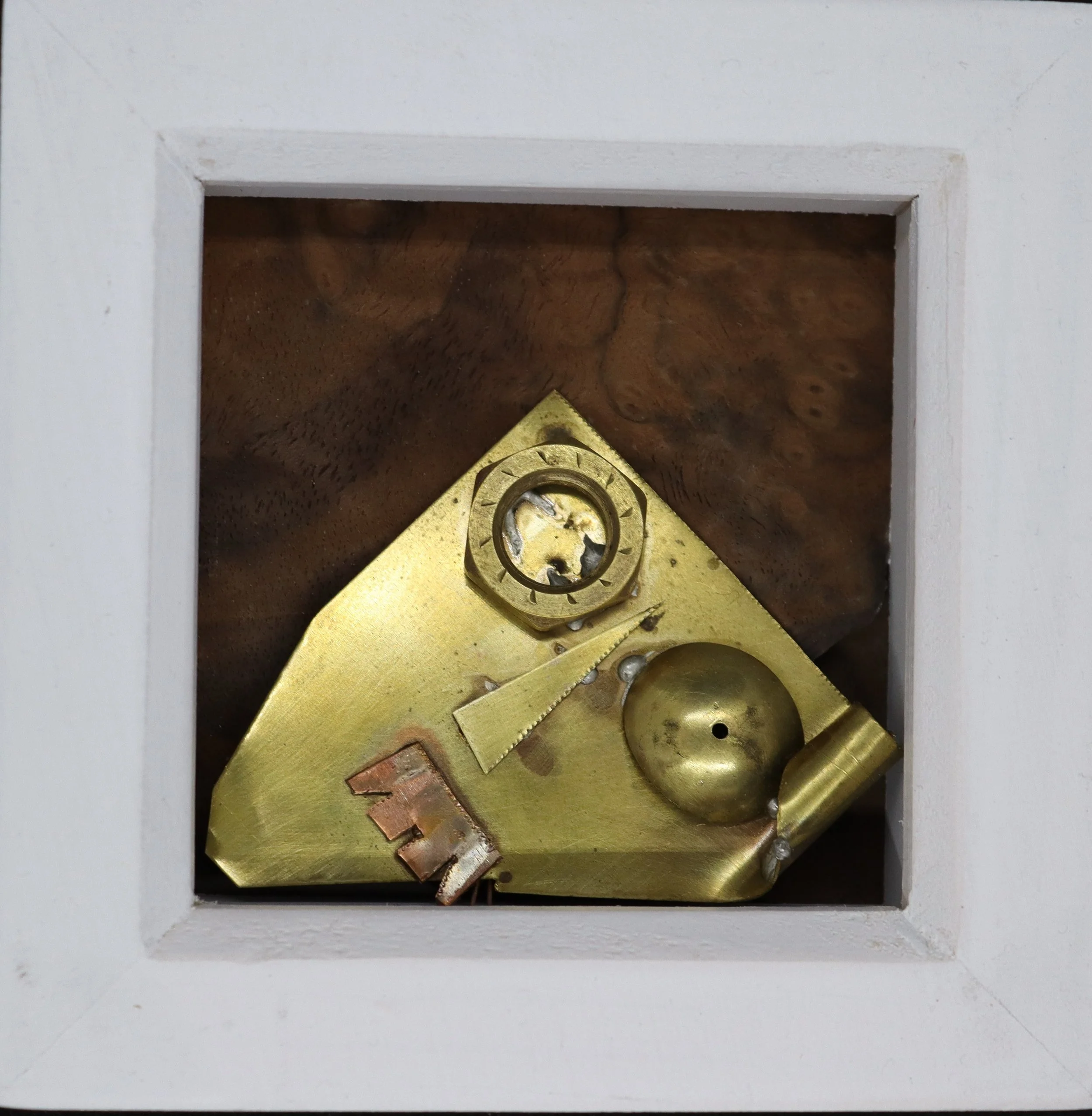 Close-up of the interior mechanics of a clock, showing gears and metallic components inside a wooden case with a white border.