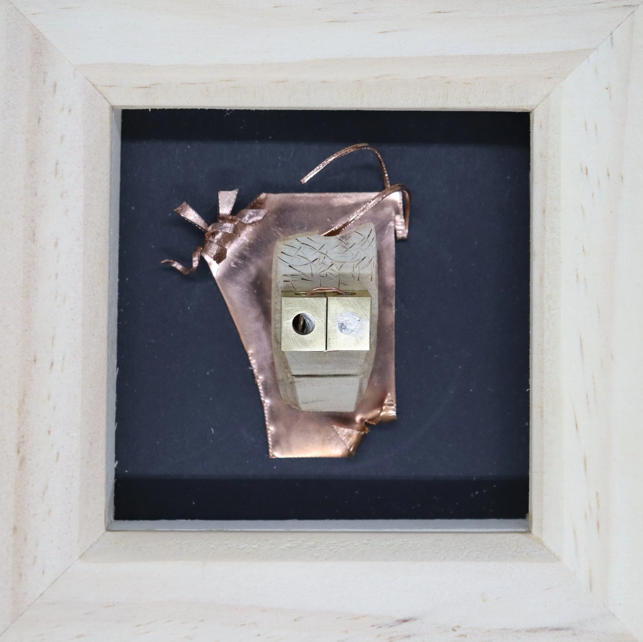 Electrical outlet with a copper wire and a metal block in a shadow box with a wooden frame.
