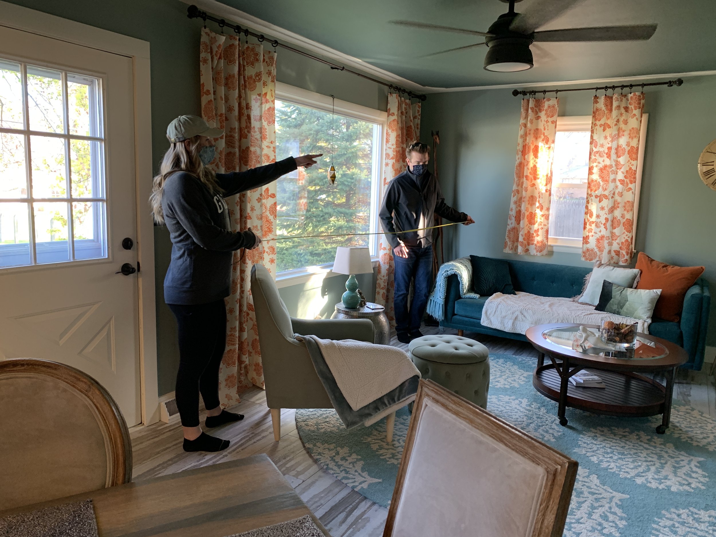 Couple holding measuring tape in living room.