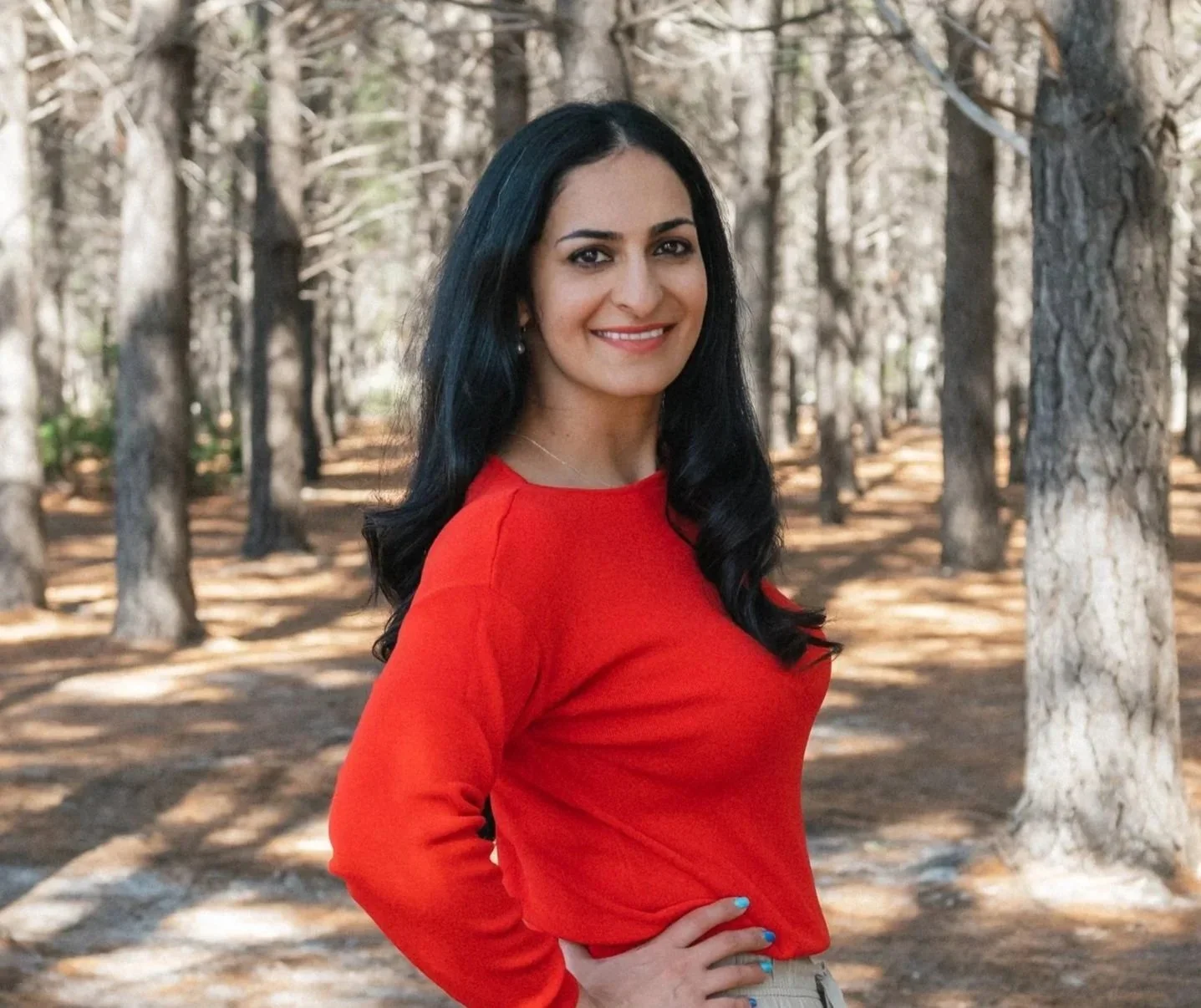 Nyla Khan, women's workshop facilitator, sitting outdoors in a forest landscape