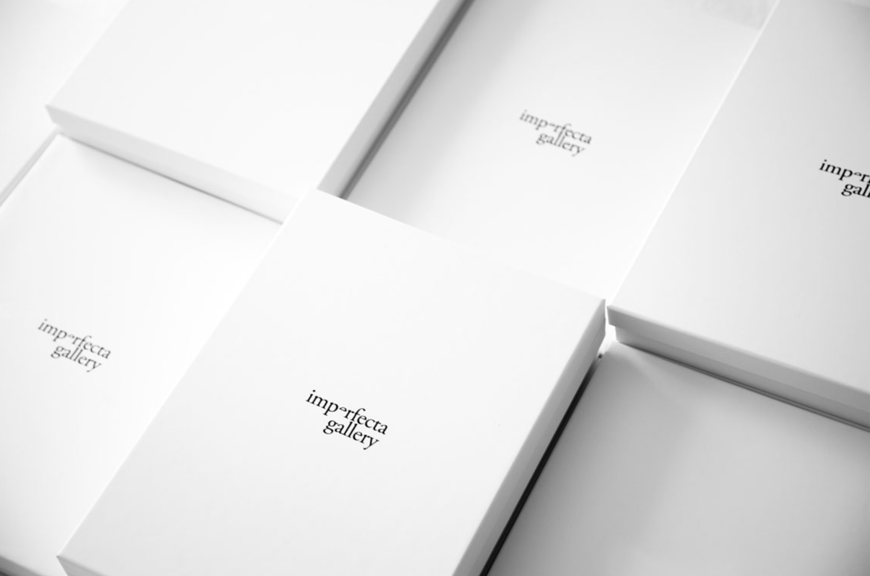 Several white boxes with transparent windows displaying the text "imperfecta gallery" inside.