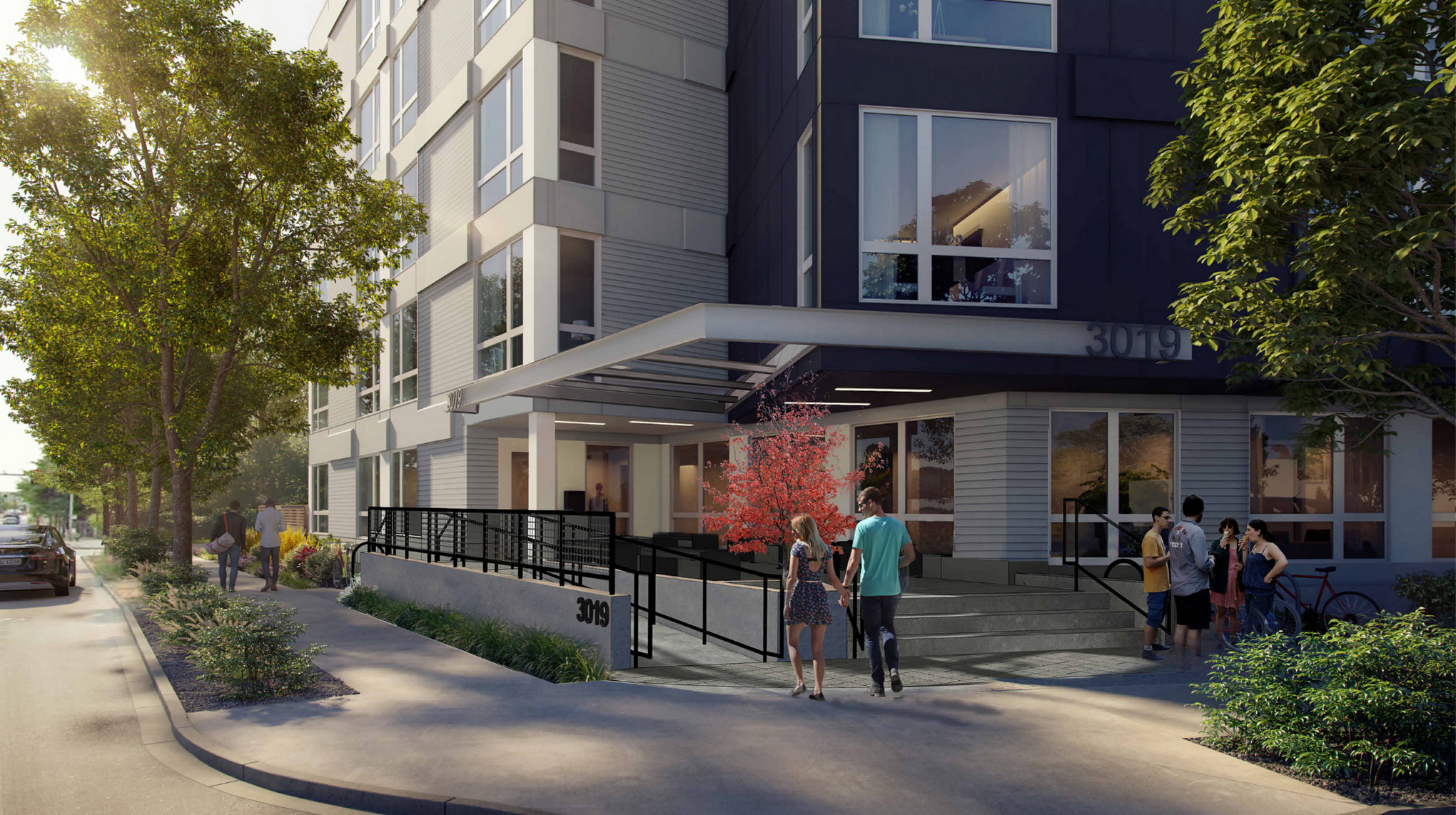 Modern apartment building entrance with people walking and socializing, surrounded by trees and greenery on a sunny day.