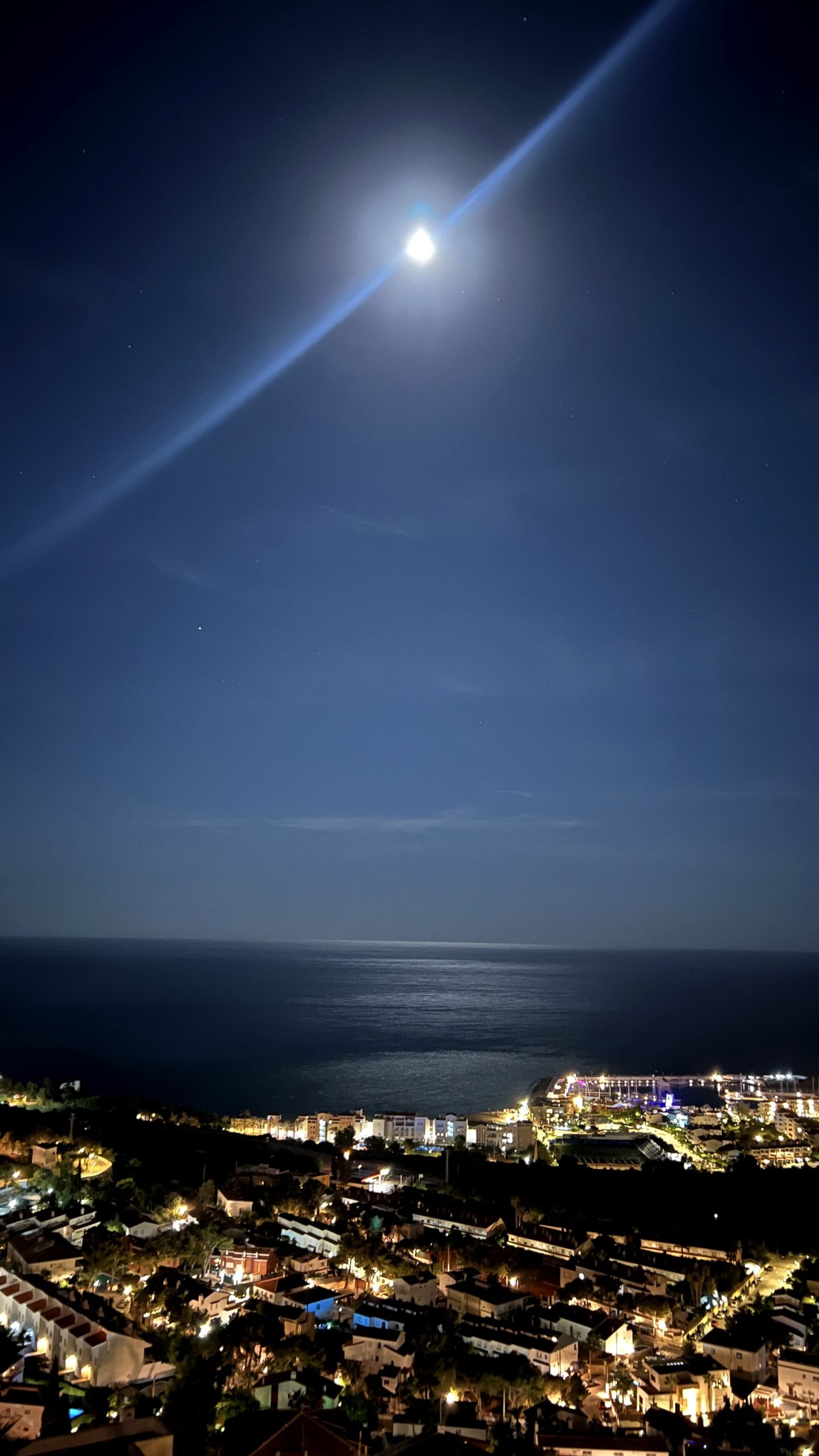 Full moon over the Mediterranean and the lights of Sitges at night