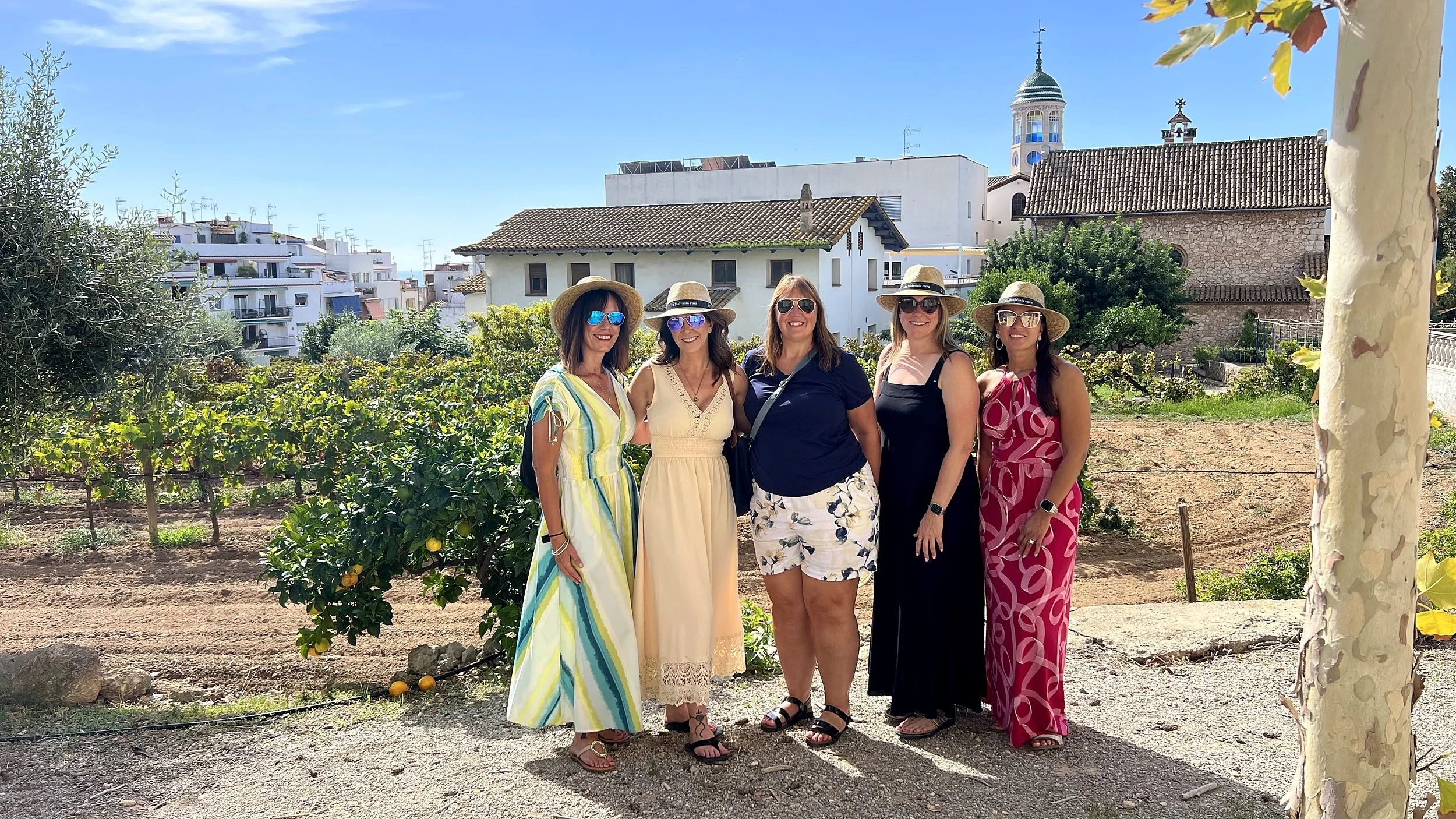 Group of women in the urban Malvasia vineyard in Sitges with a historic church behind them