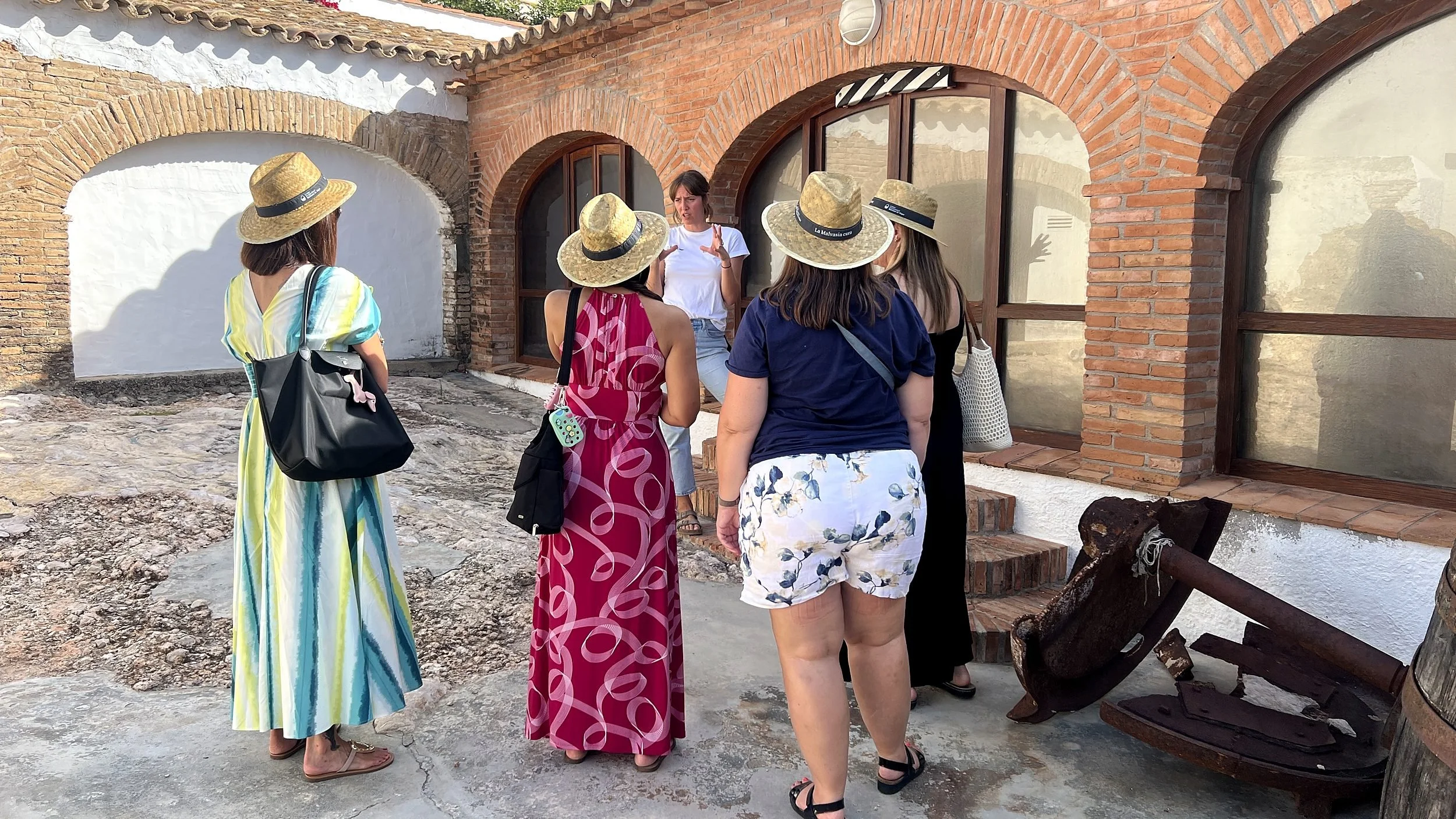Women in sun hats on a guided tour of the Celler de l’Hospital winery courtyard in Sitges