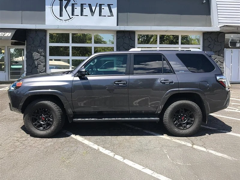 A black SUV parked in an angled parking space outside a building with the sign "Keeves."