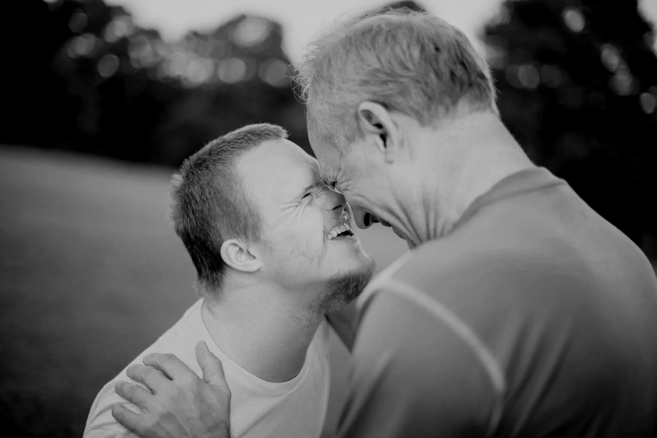 Two men are touching foreheads and smiling.