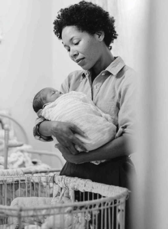 A woman holding a newborn baby in a hospital room.