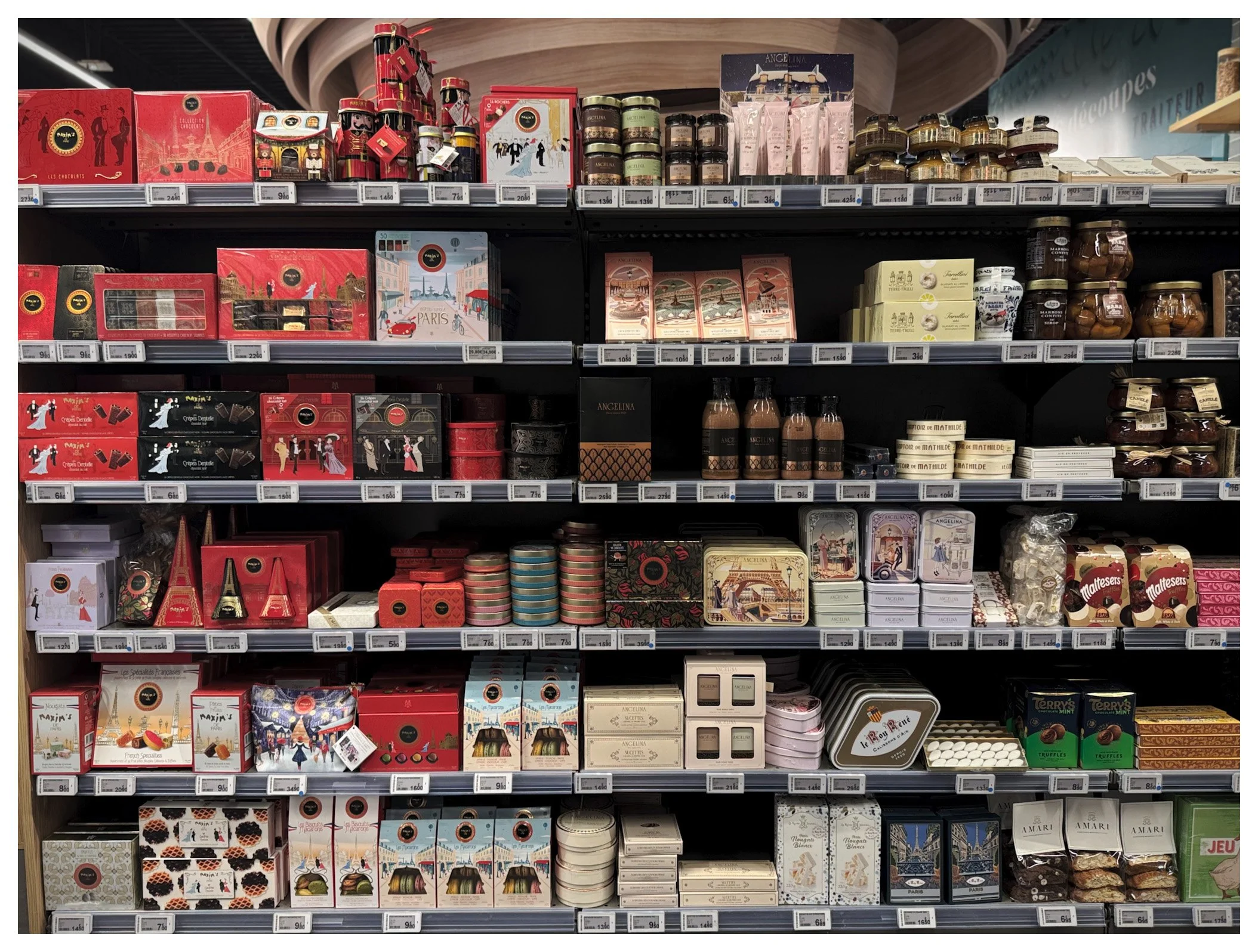 Shelf filled with various boxed chocolates, pralines, and confectionery in decorative packaging.