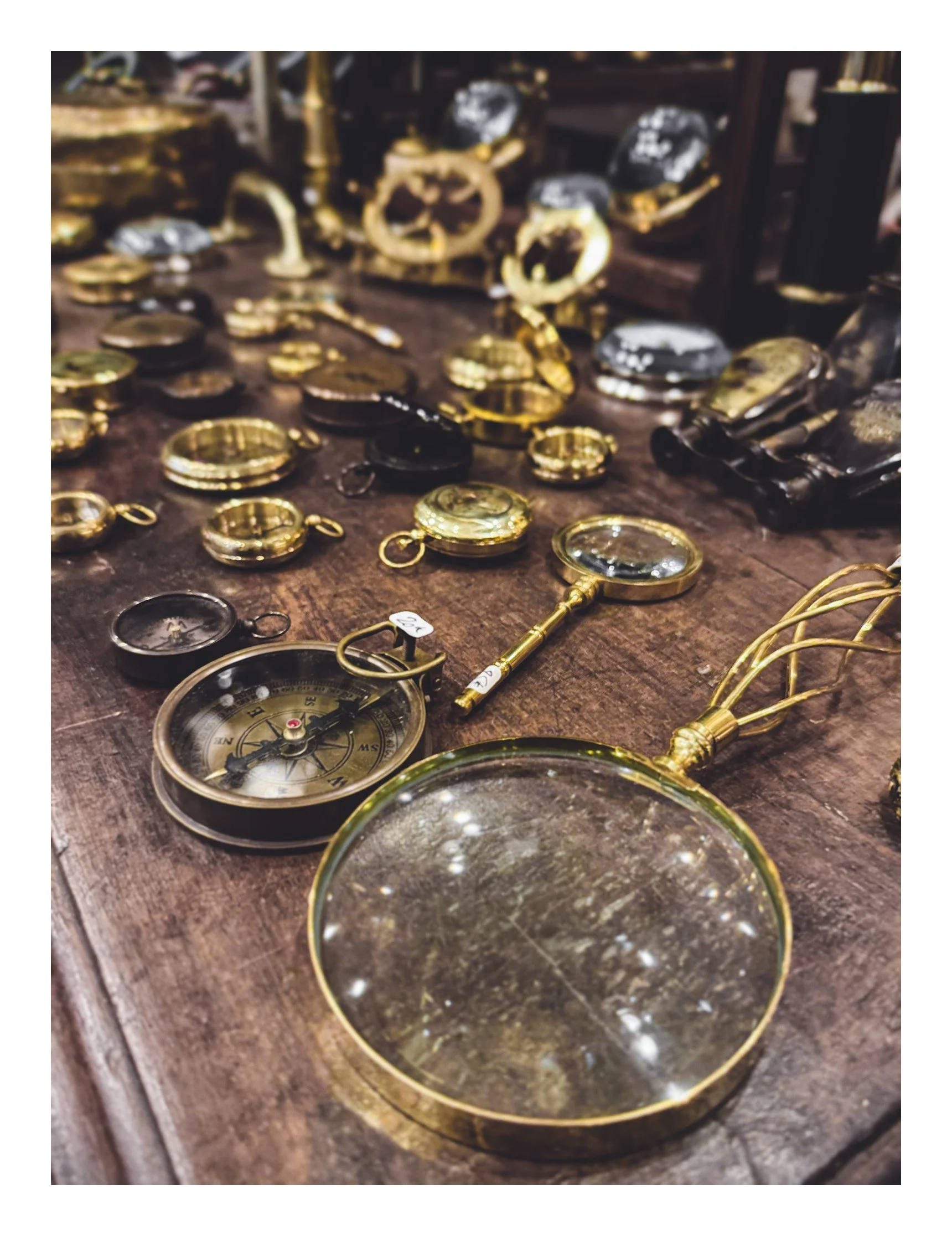 Various vintage gold and silver pocket watches and compasses displayed on a wooden table.