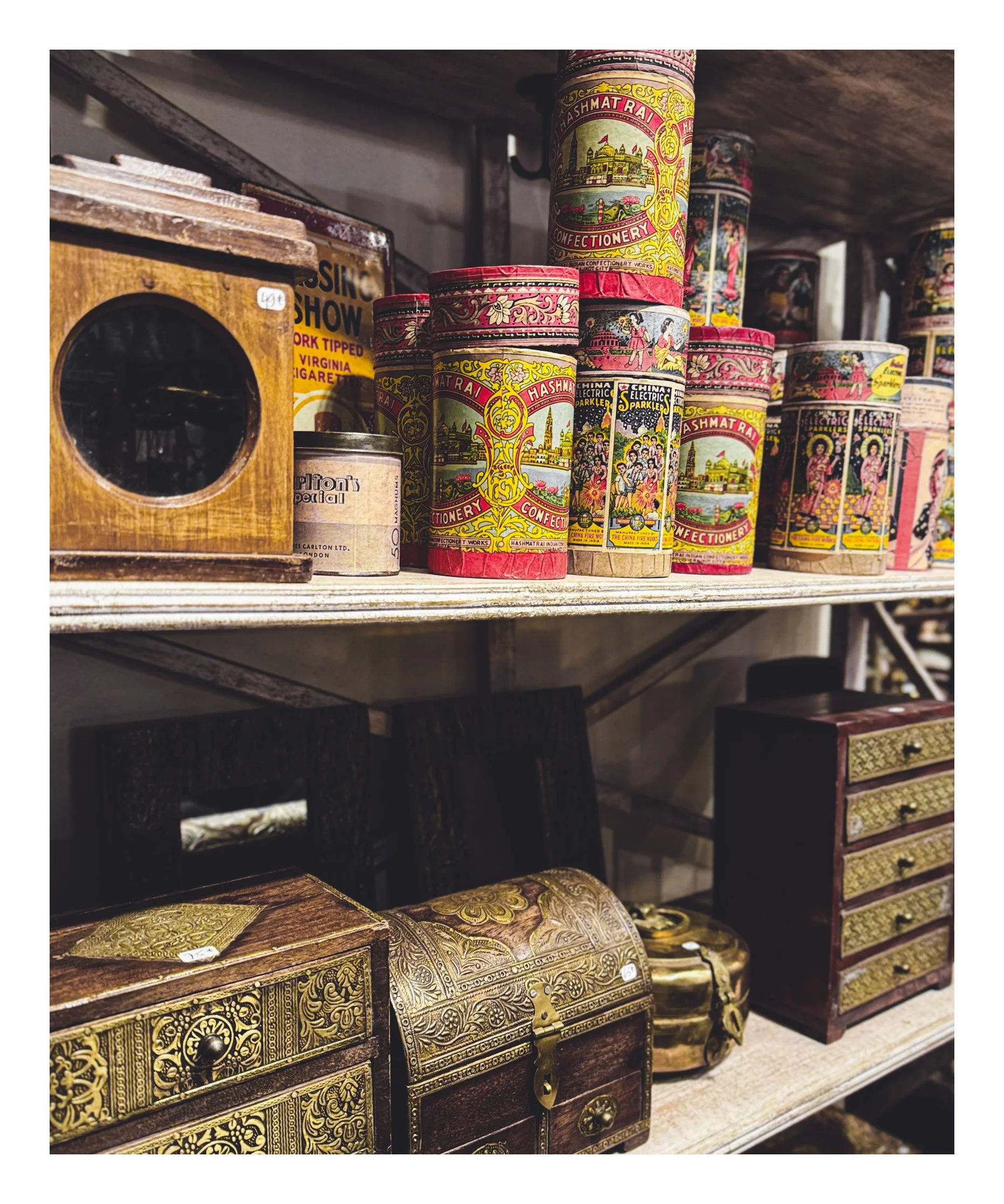Shelf displaying vintage tins of Hashmat Rai confectionery and collectible boxes with intricate designs.