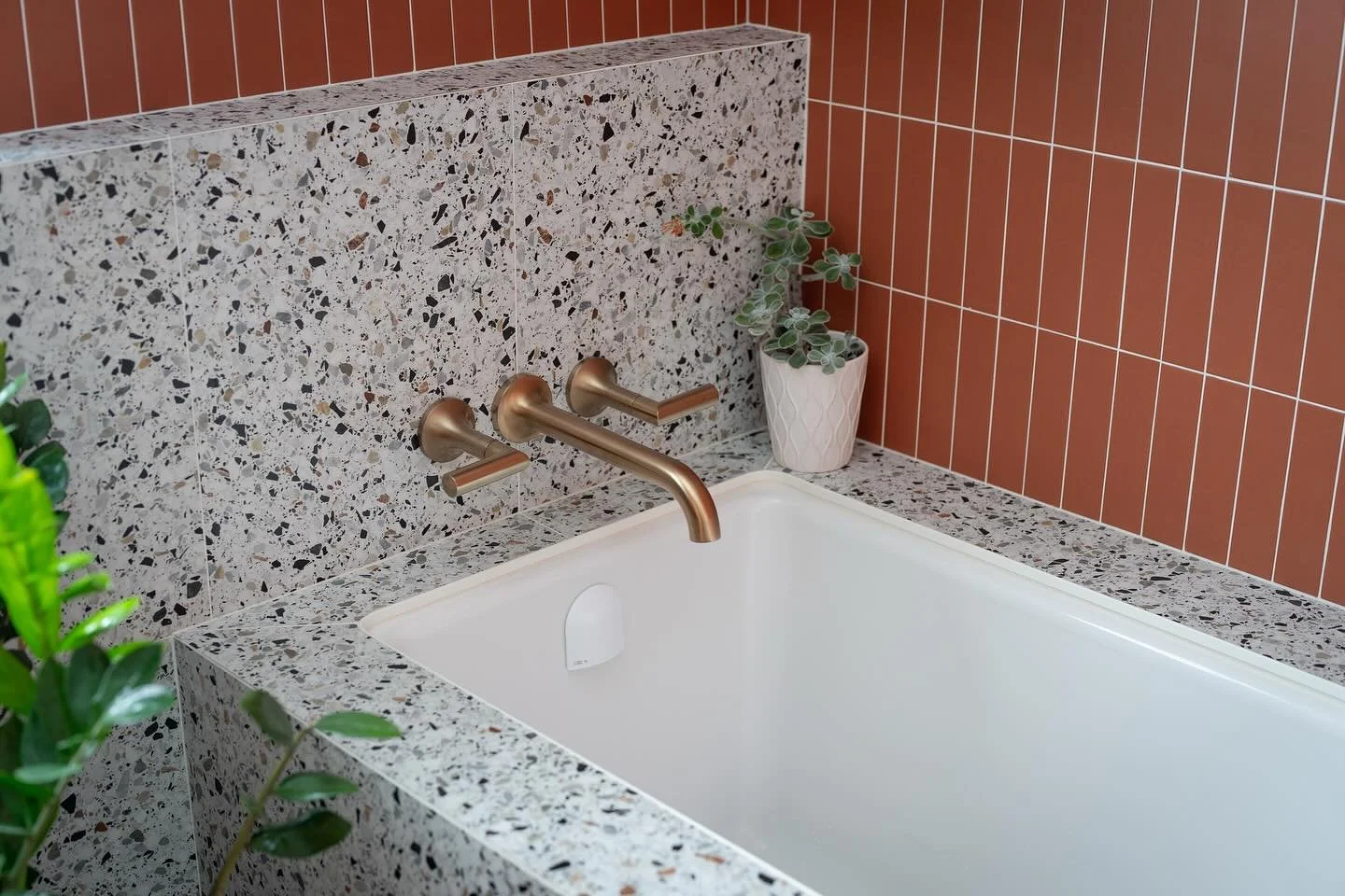 An undermount tub is a great way to add a bit of flare to a bathroom. 95% of bathrooms are too small for a free standing tub IMO, and full acrylic tubs with splash guards are just a necessary evil. 
You can clad these in whatever medium you choose, a