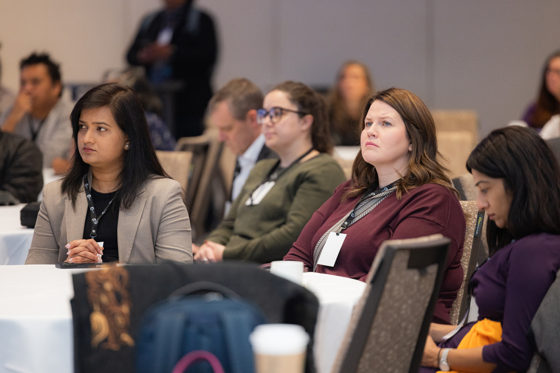 Attendees sitting at conference tables listening to a presentation during a formal professional event.
