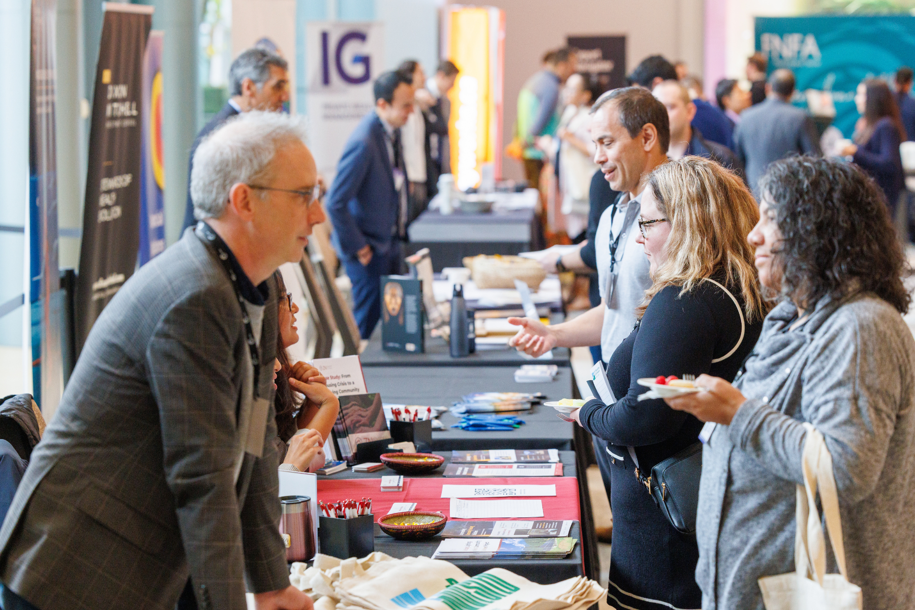 People at a professional conference or expo interacting at booths with banners and informational materials.