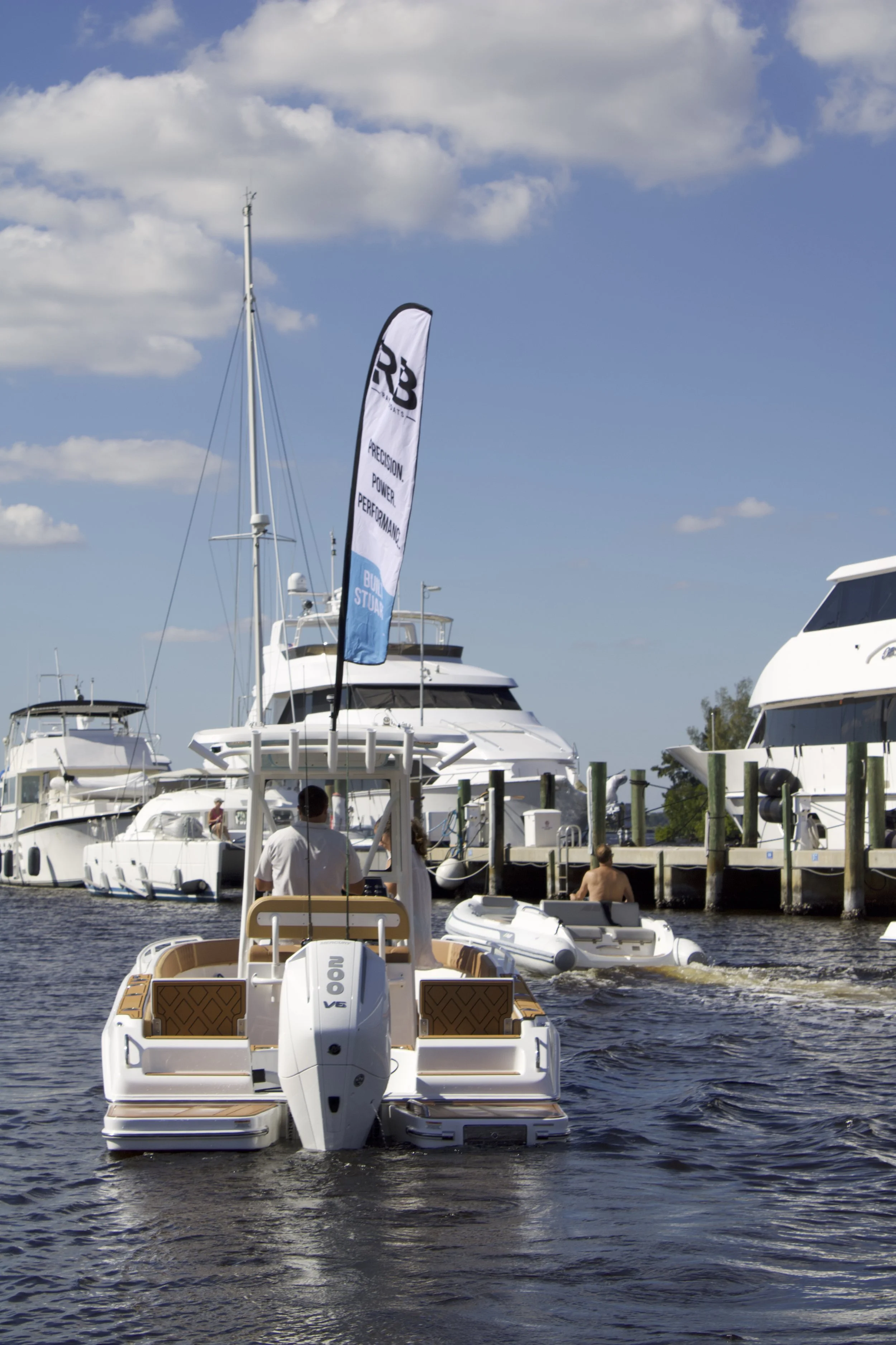 A boat in a marina with other yachts and boats docked, with a blue sky and scattered clouds overhead.
