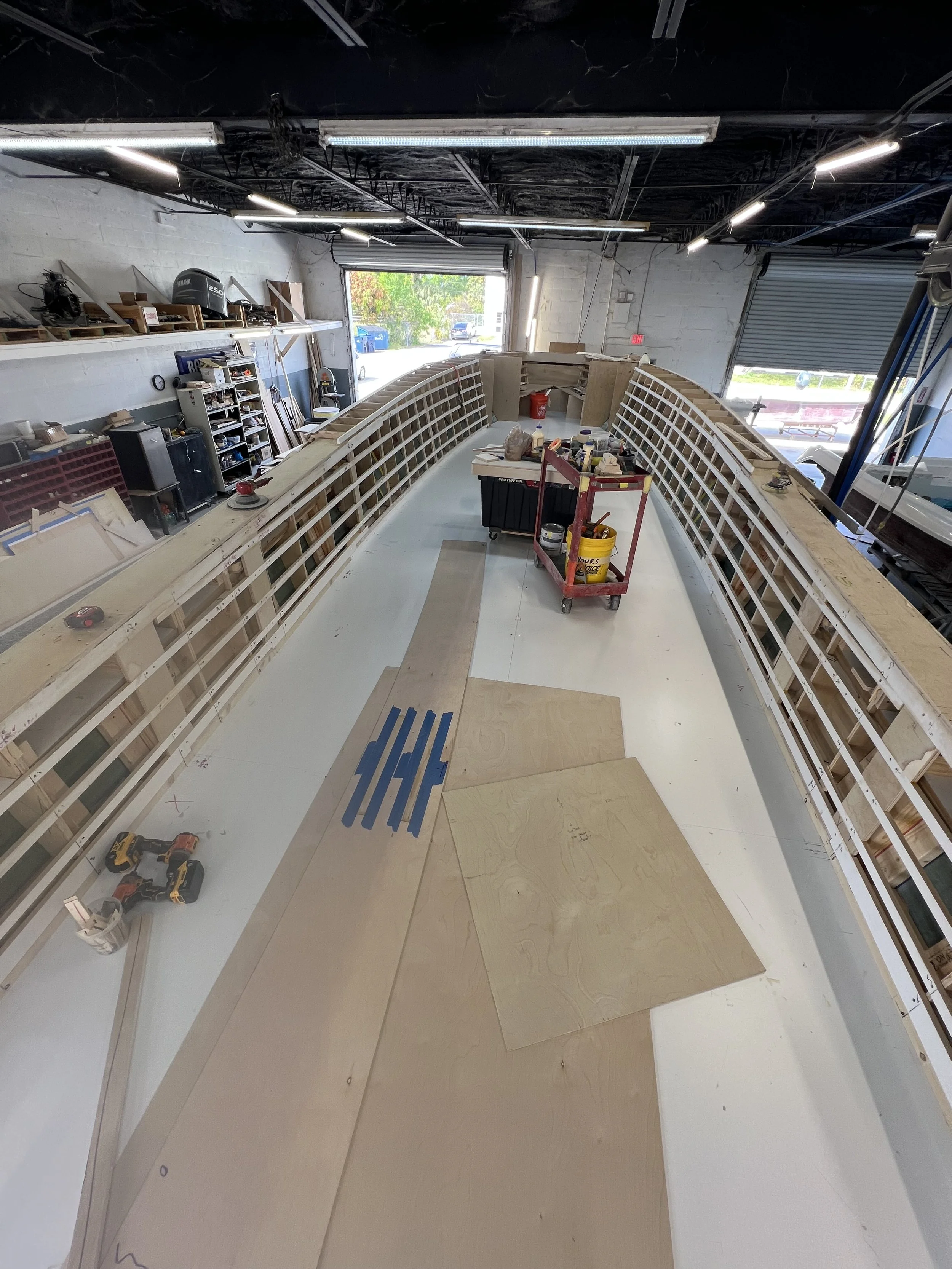 Under construction boat with wooden frame and tools inside a workshop.