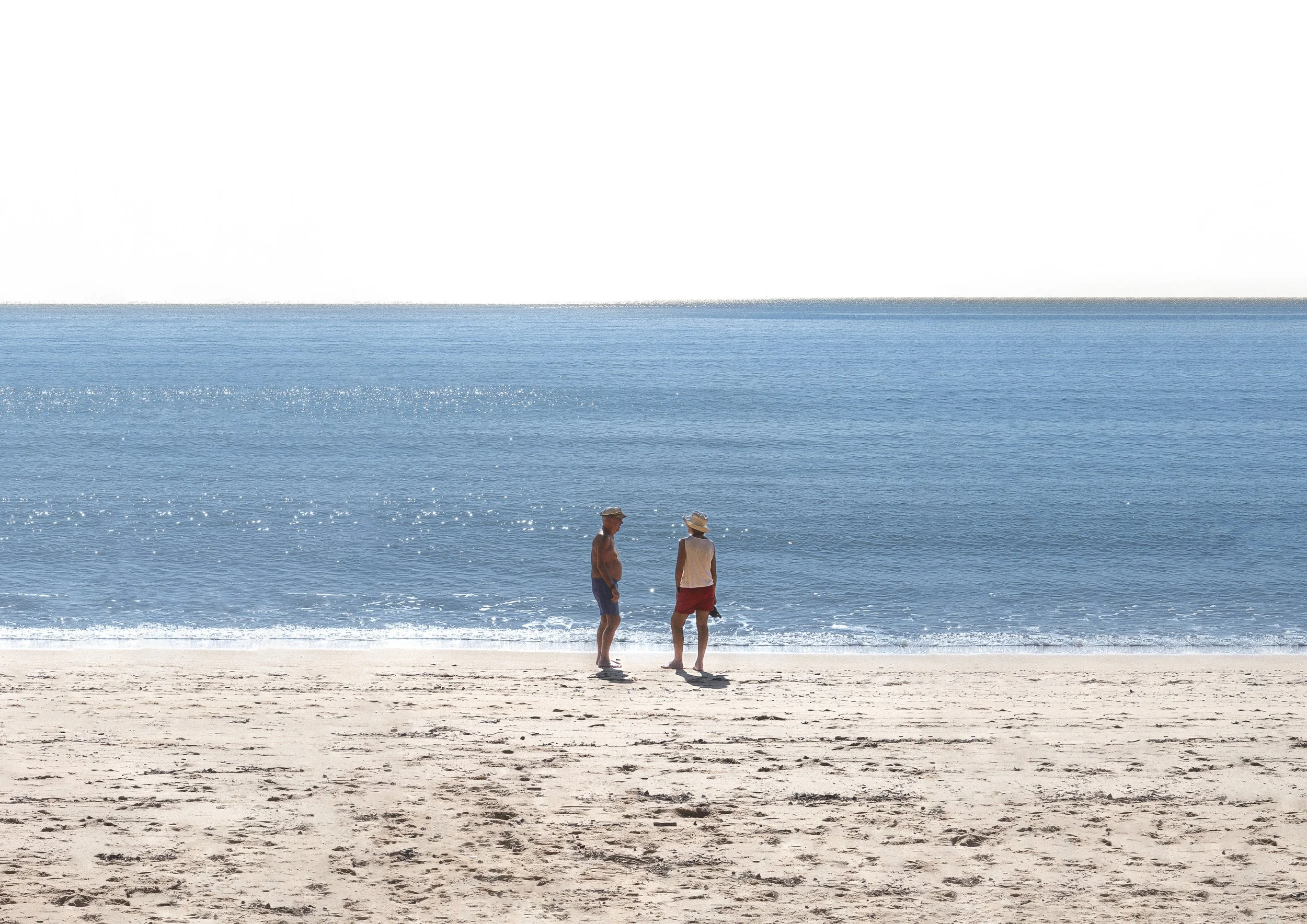 An elderly couple on a vast beach with ocean