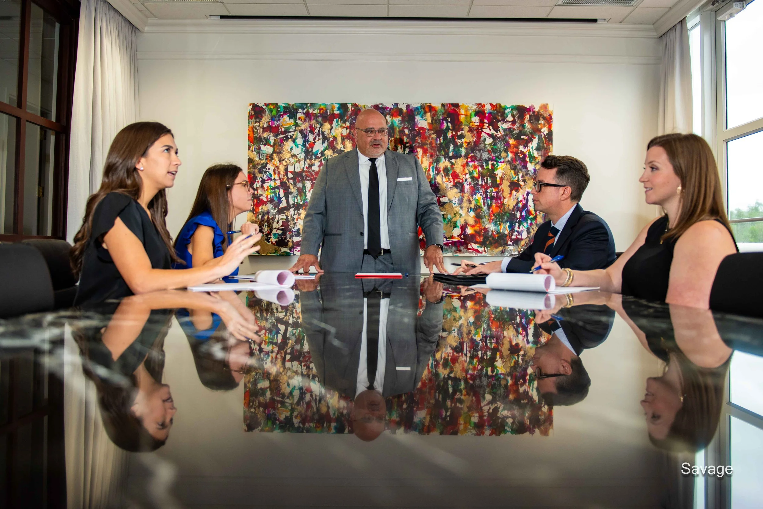 Group of business people in a meeting in a conference room with colorful art on the wall.