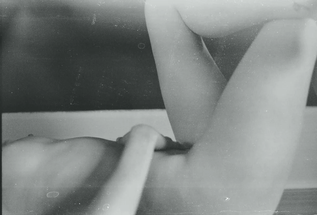 Black and white photo of a person lying down with knees bent, captured from the side.