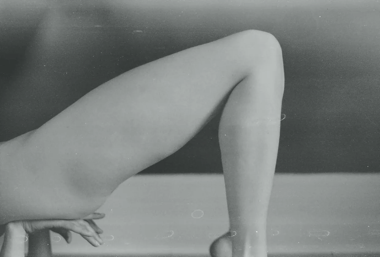 Black and white image of a person's legs supported by their hands.