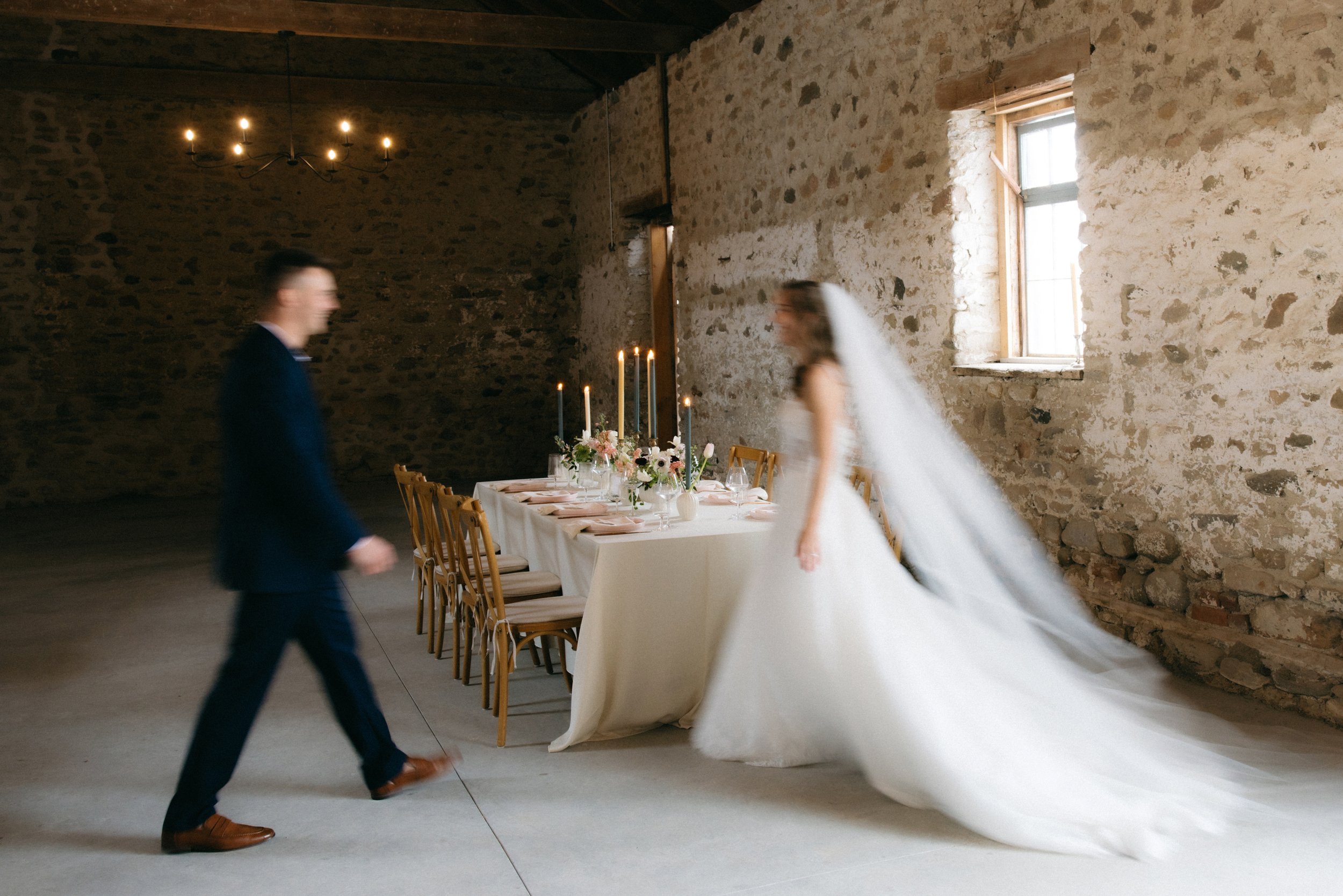 A blurred, cinematic capture of a couple at their wedding reception, highlighting the warm atmosphere created by site-responsive event styling and candlelight.