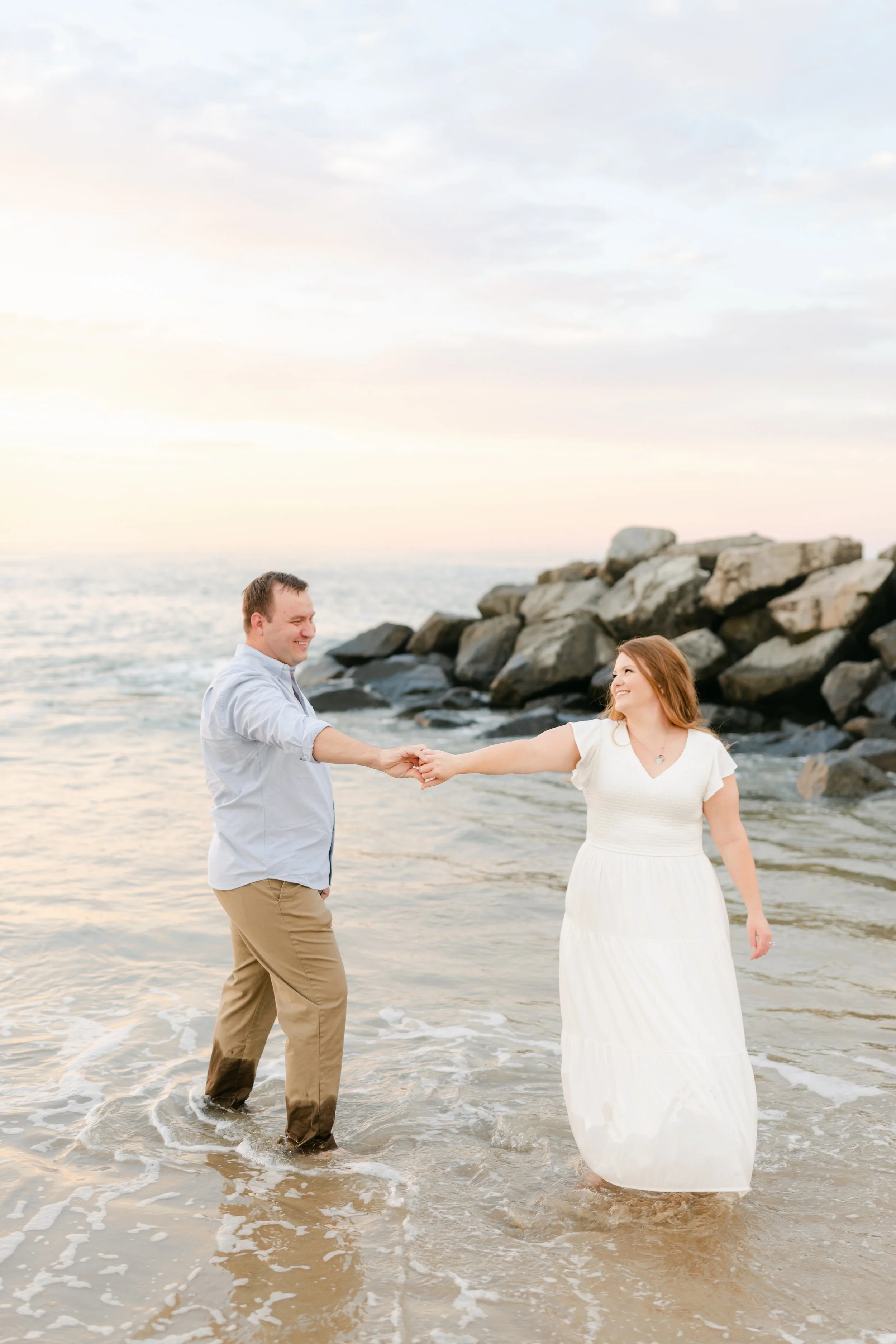 Virginia Beach family photography at sunset — candid ocean moment with couple standing in the waves during lifestyle session