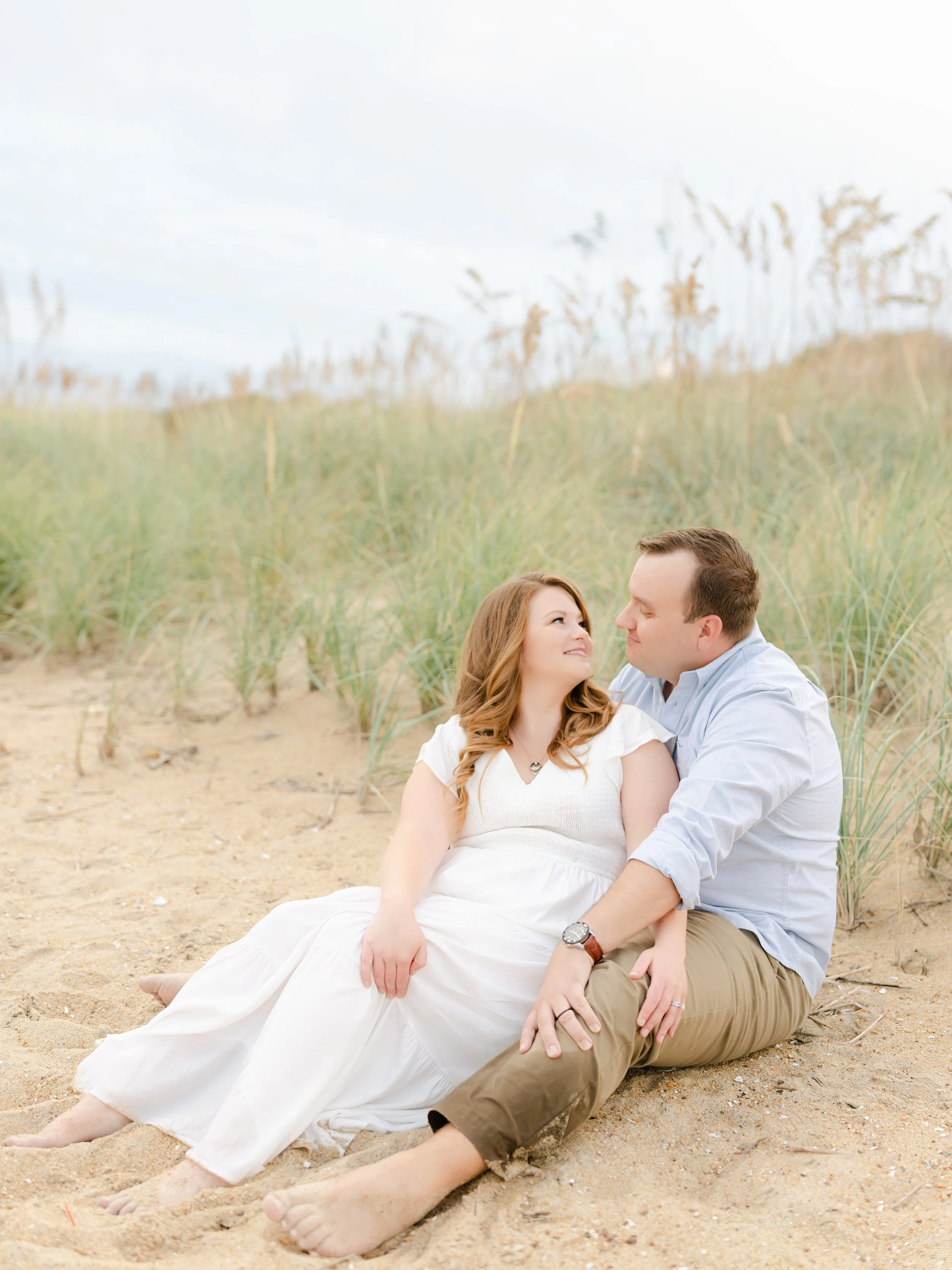 Light and airy engagement session on a Virginia Beach sand dune, with a couple embracing at sunset