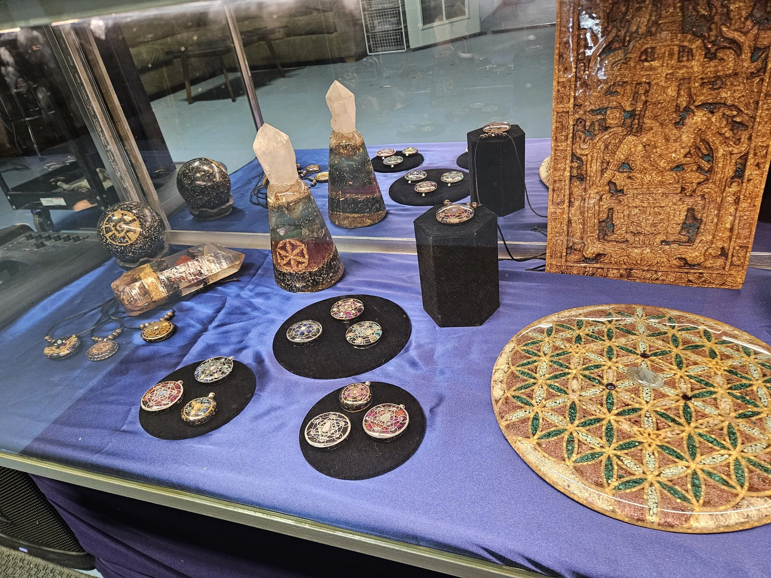 Daylight display case with handmade orgone pendants on blue cloth