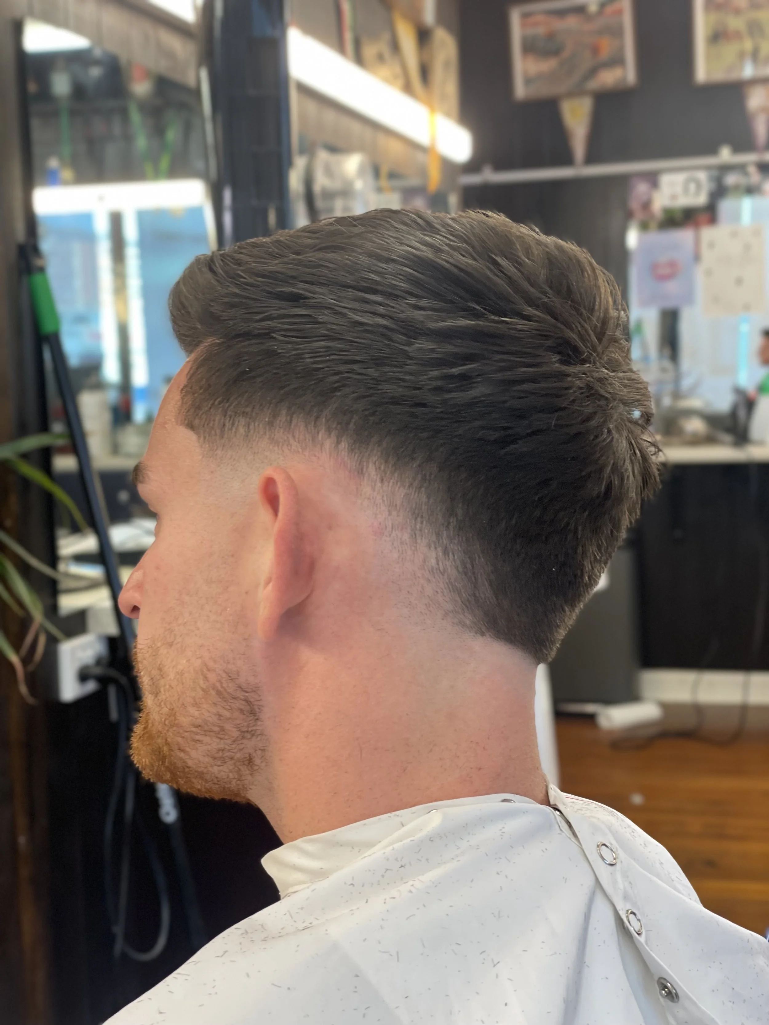 Back view of a person with a fresh haircut, featuring a faded undercut style, in a barber shop setting. best sligo fade haircut irish barber review