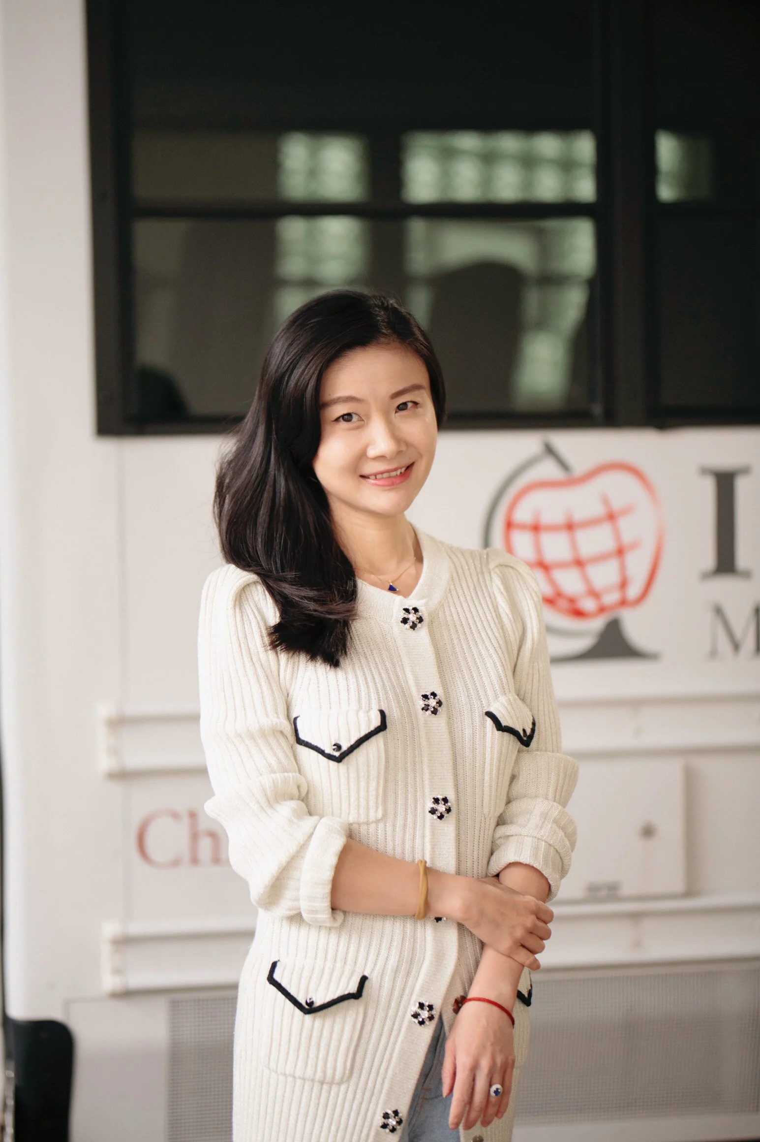 Woman in a white dress with long black hair, smiling against a white background.