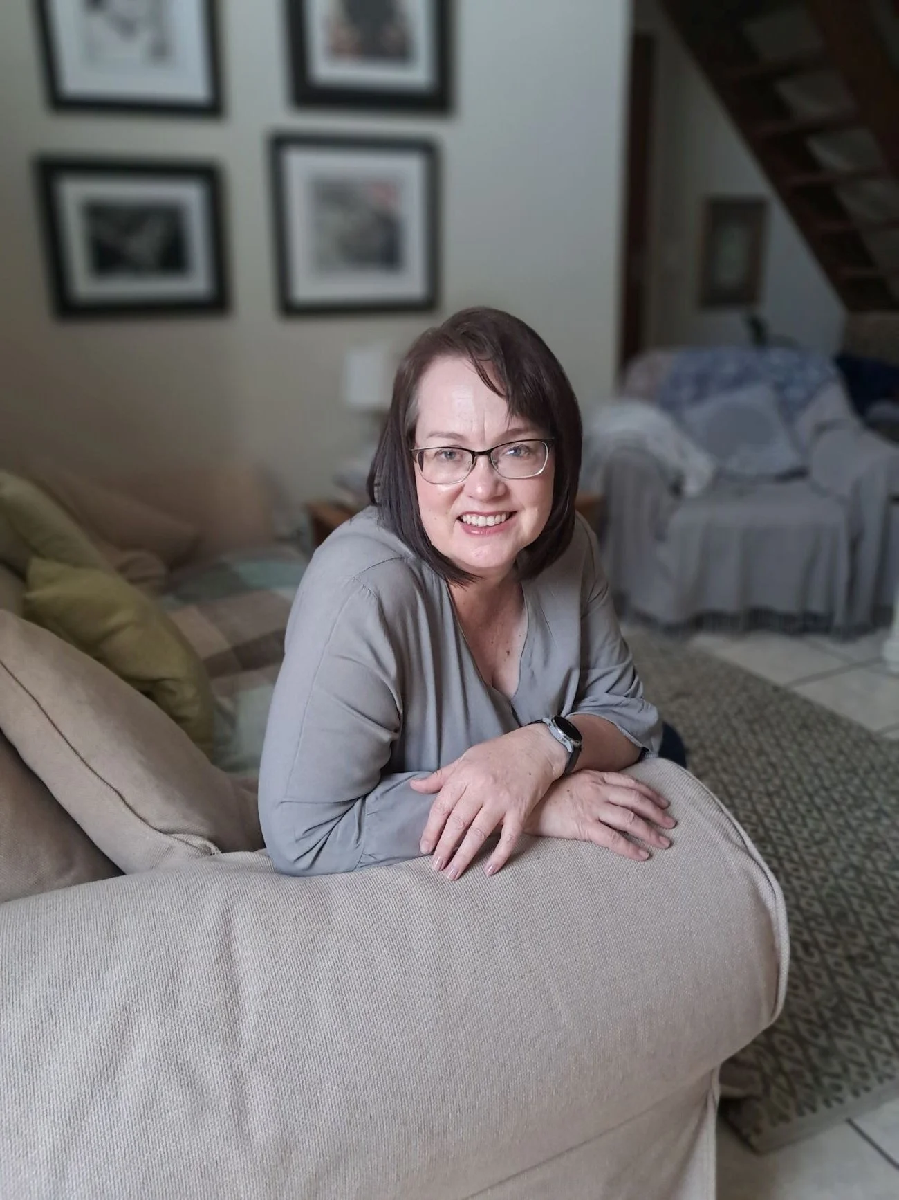 woman-with-glasses-sitting-on-couch-neutral-background