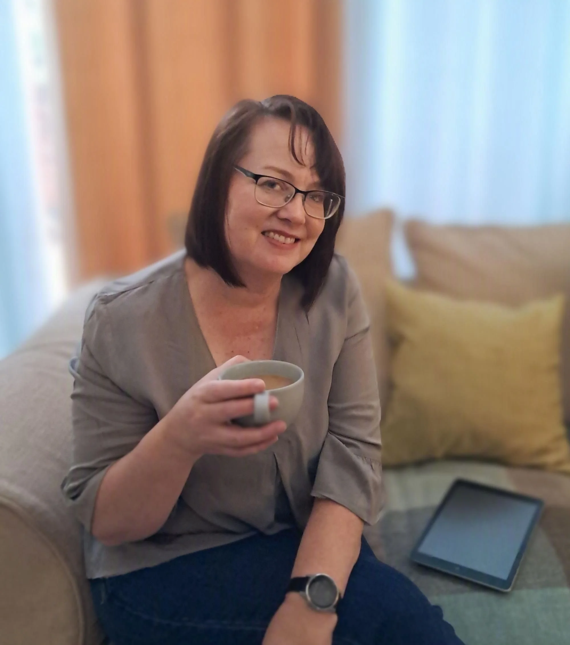 woman-with-glasses-sitting-on-couch-with-coffee-cup