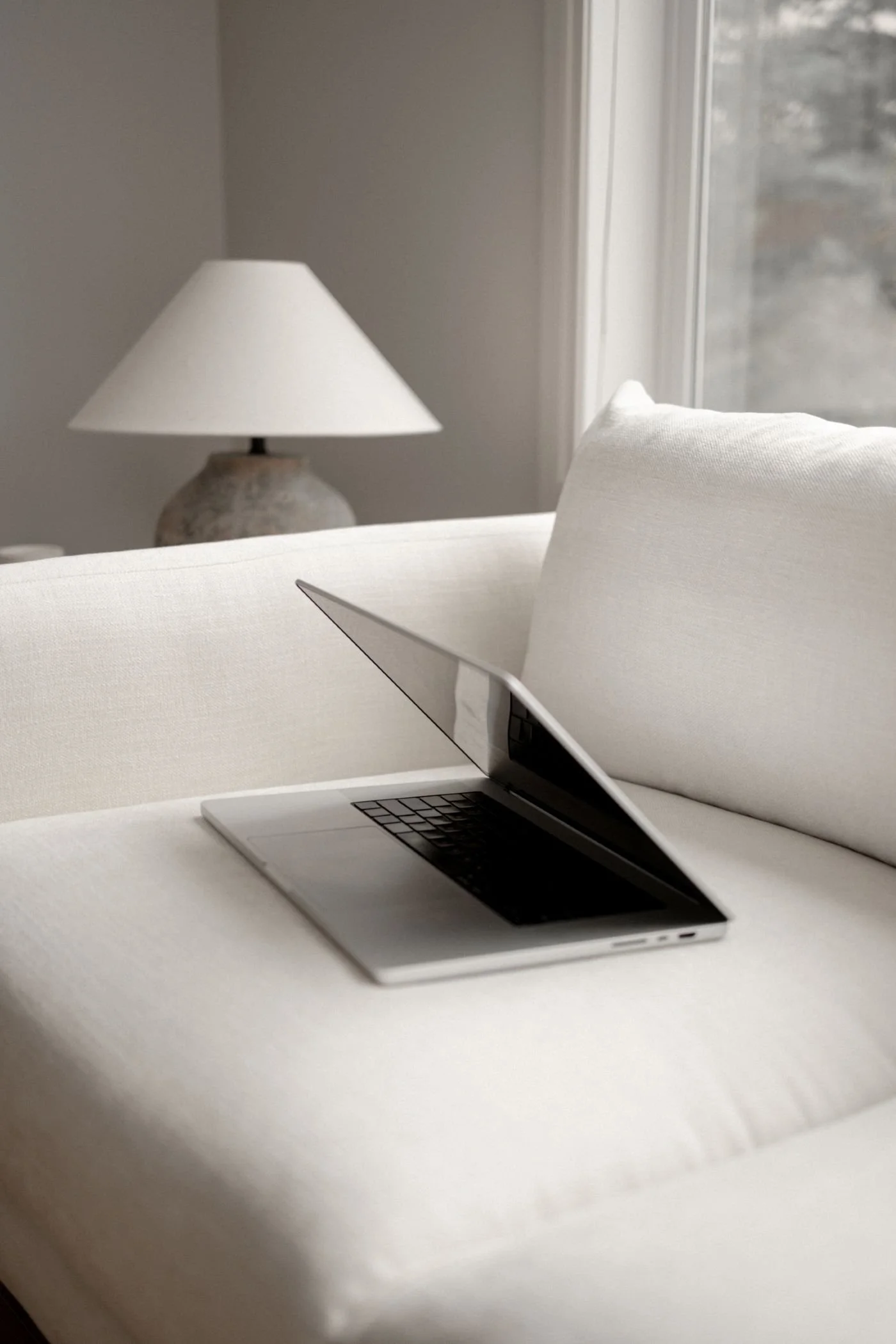 open-laptop-on-beige-couch-beige-lamp