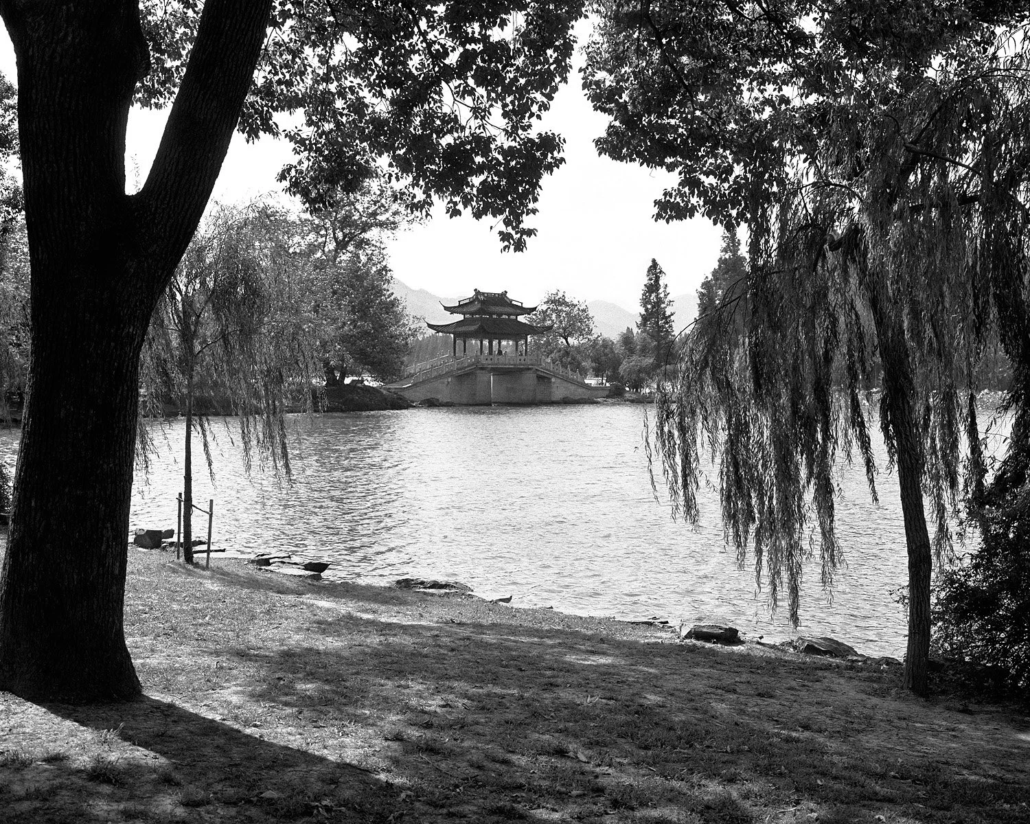 Gengbo Pavilion across West Lake in Hangzhou, framed by trees along the shoreline, photographed in 2003.